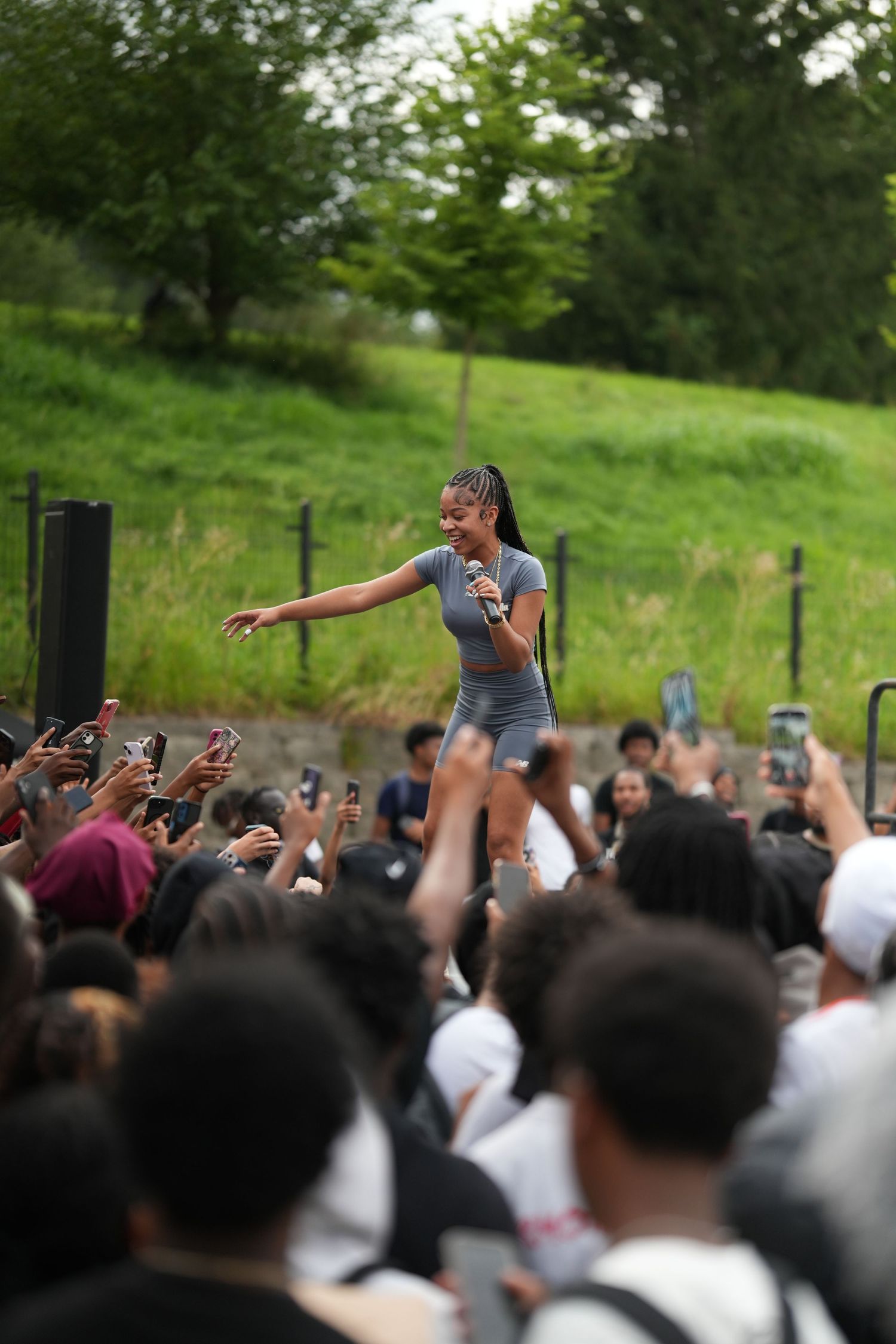 Large crowd at an outdoor event with raised phones and cameras capturing a performance.