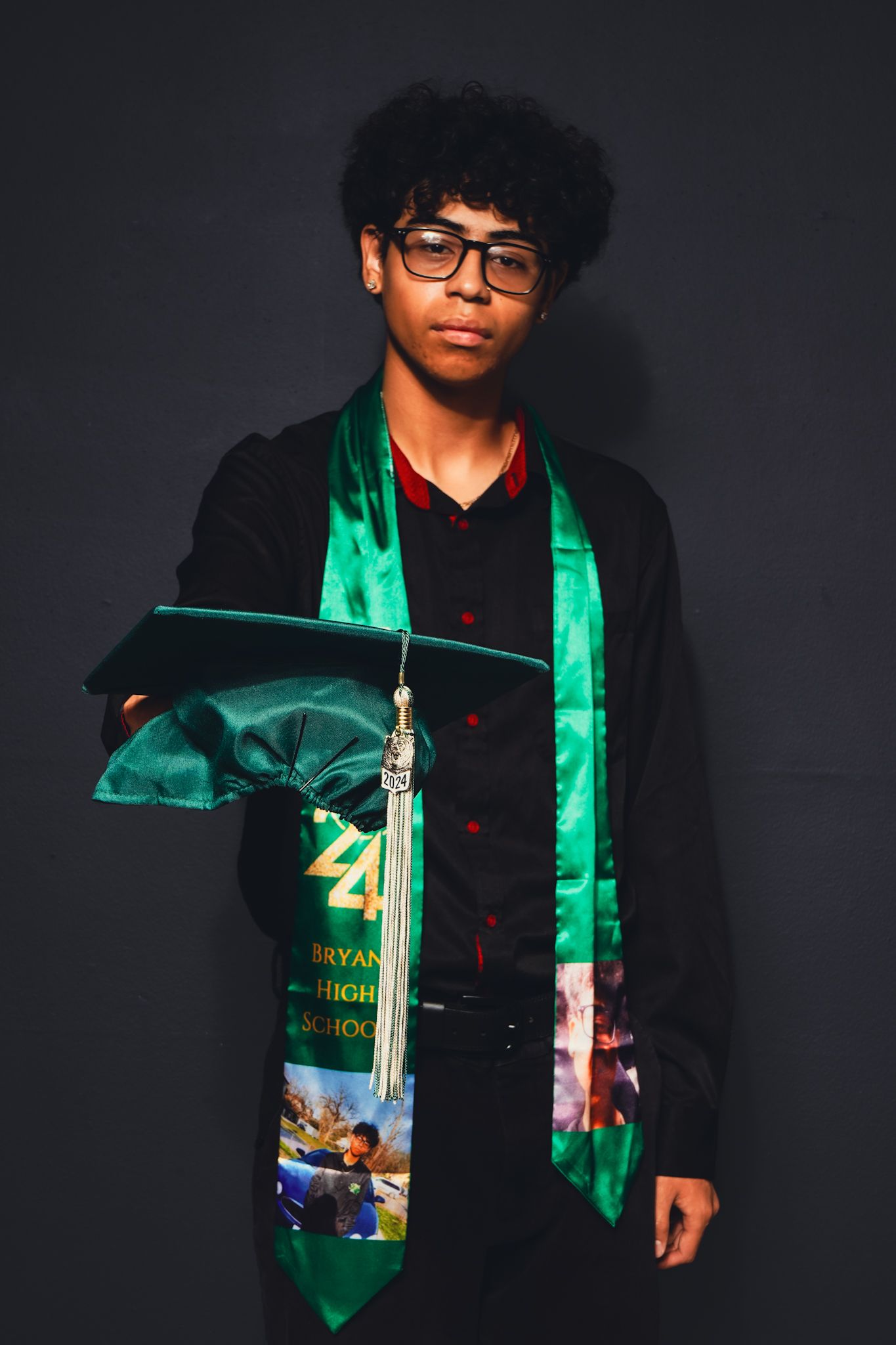 Graduate wearing a green graduation stole and black outfit poses for a series of celebratory photos.