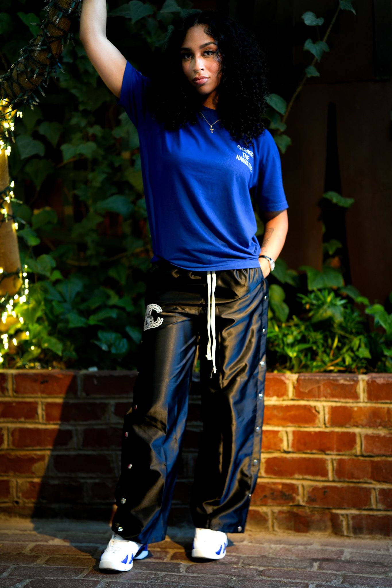 Four sequential photos show a person in a blue shirt and dark pants posing against a brick wall with green foliage.