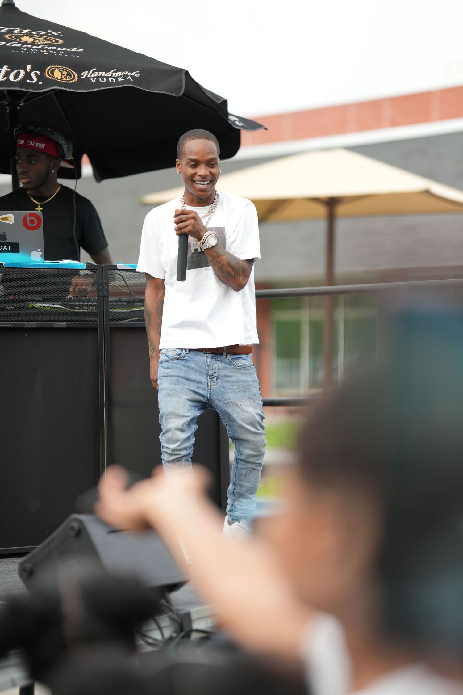 Person in ripped jeans and white t-shirt standing outdoors near a black canopy tent.