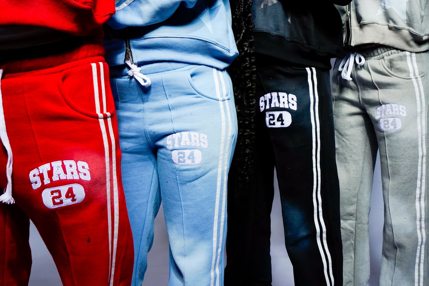A row of people wearing red and white sports jerseys with 'STARS' text and light blue jeans standing together.