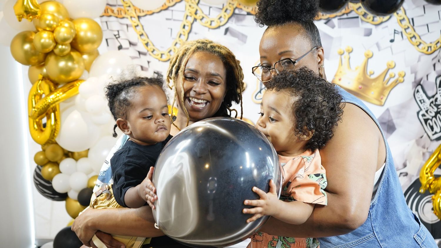 People celebrating at a party with gold balloons and decorations.