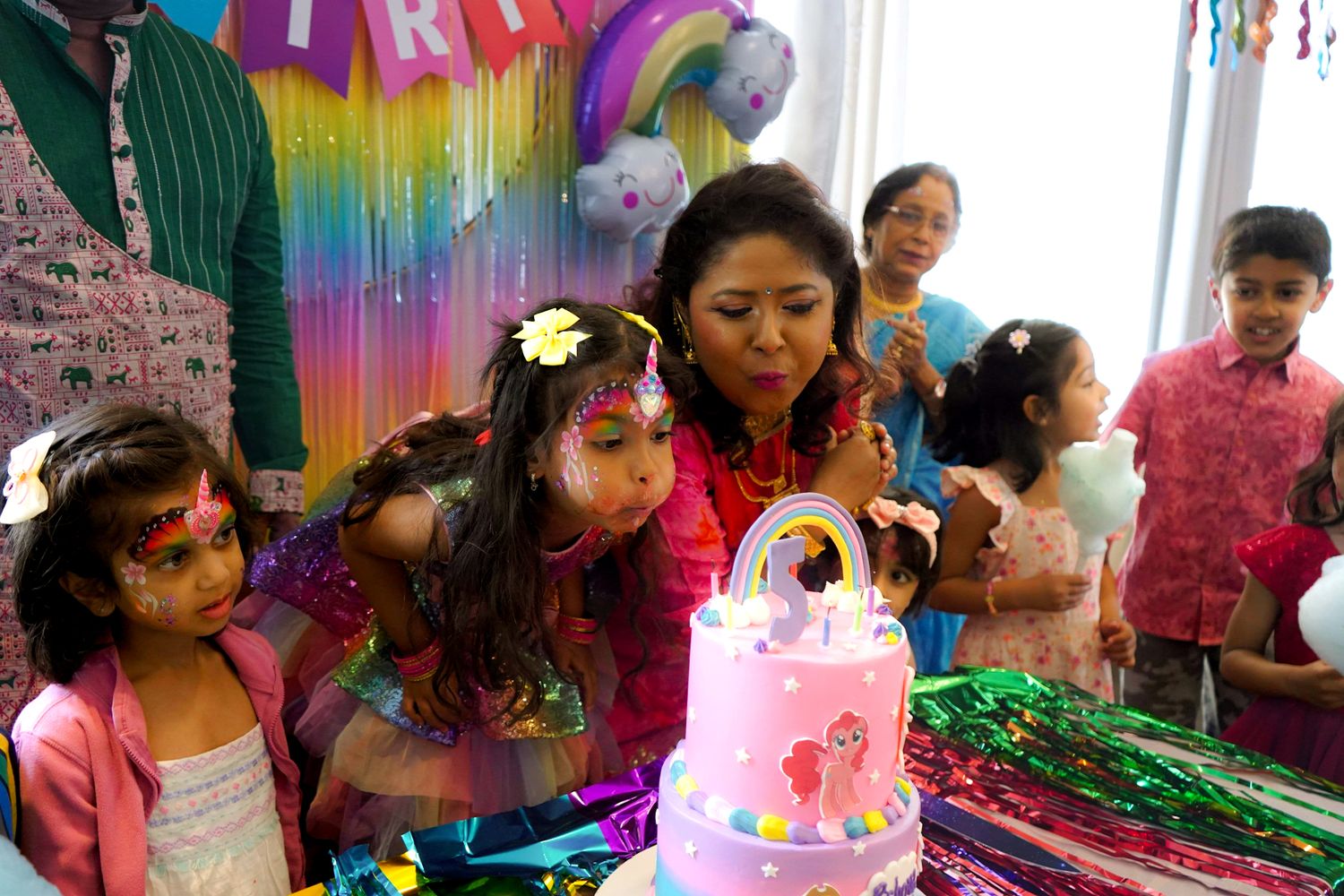 Colorful birthday party celebration with rainbow decorations and pink accents.