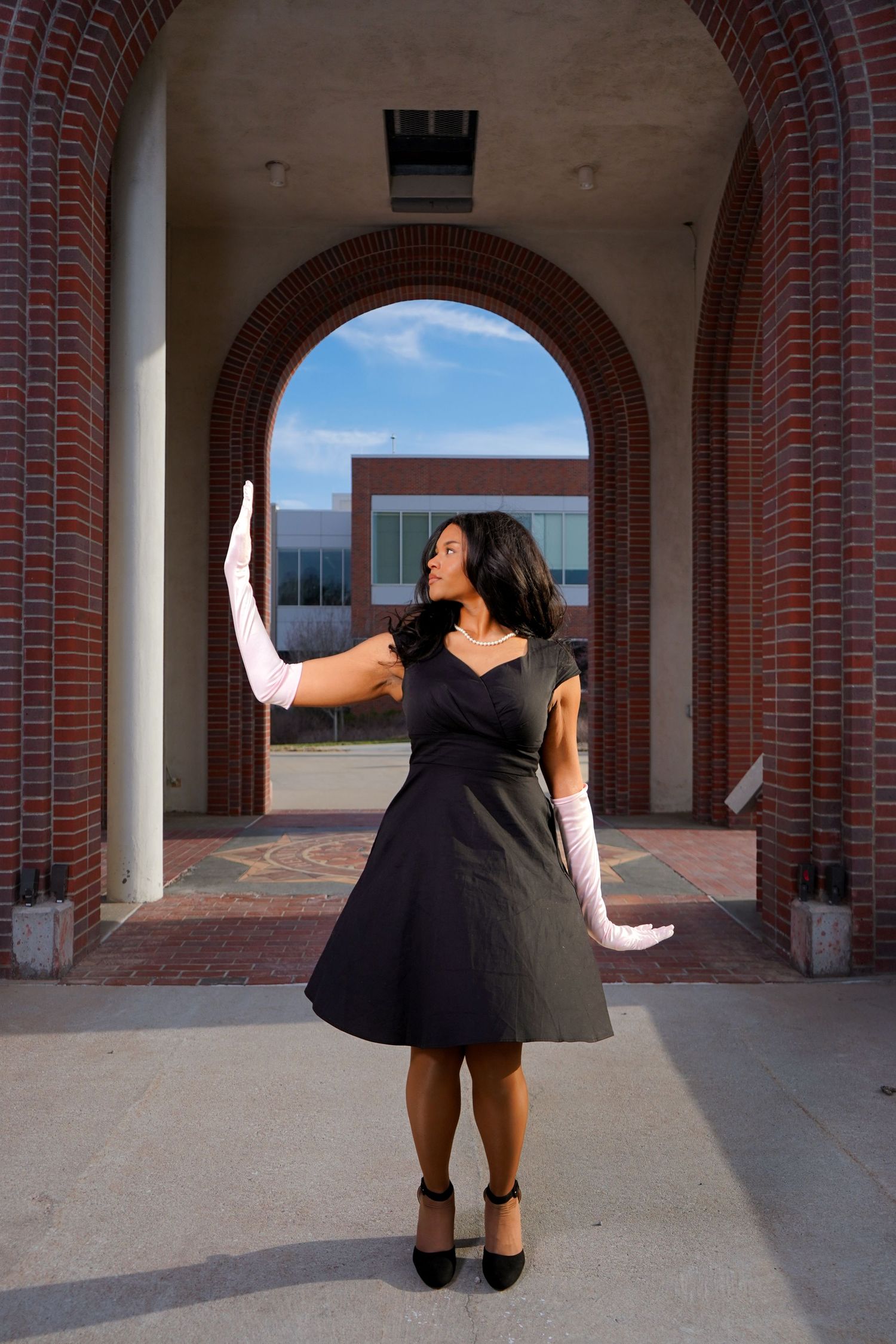 A series of artistic photos showing a person in black clothing jumping and posing under brick archways.