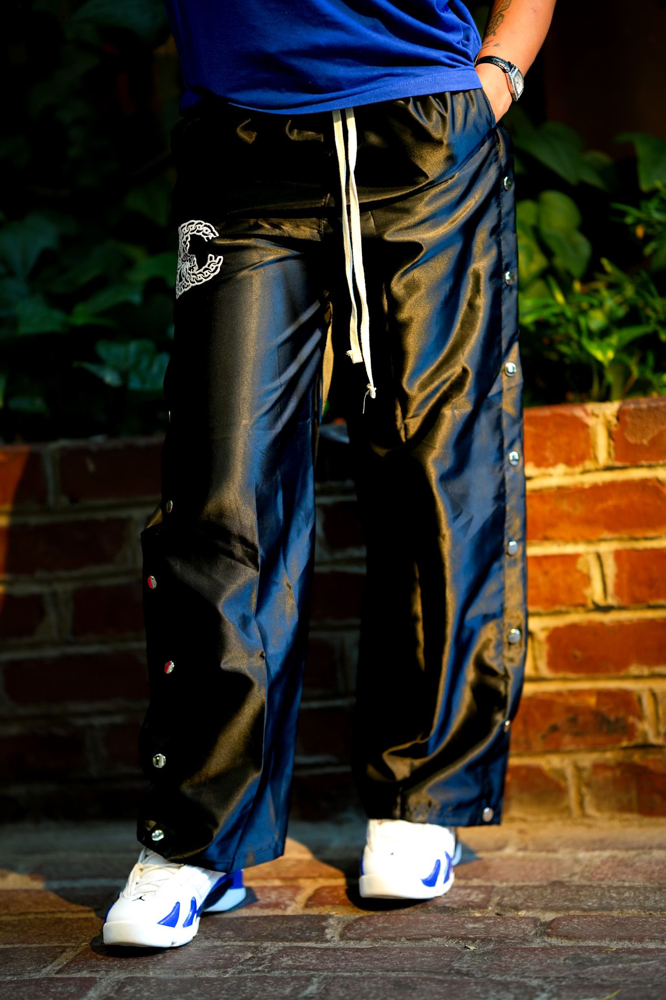 Close-up shots of blue pants and white sneakers against brick wall background.