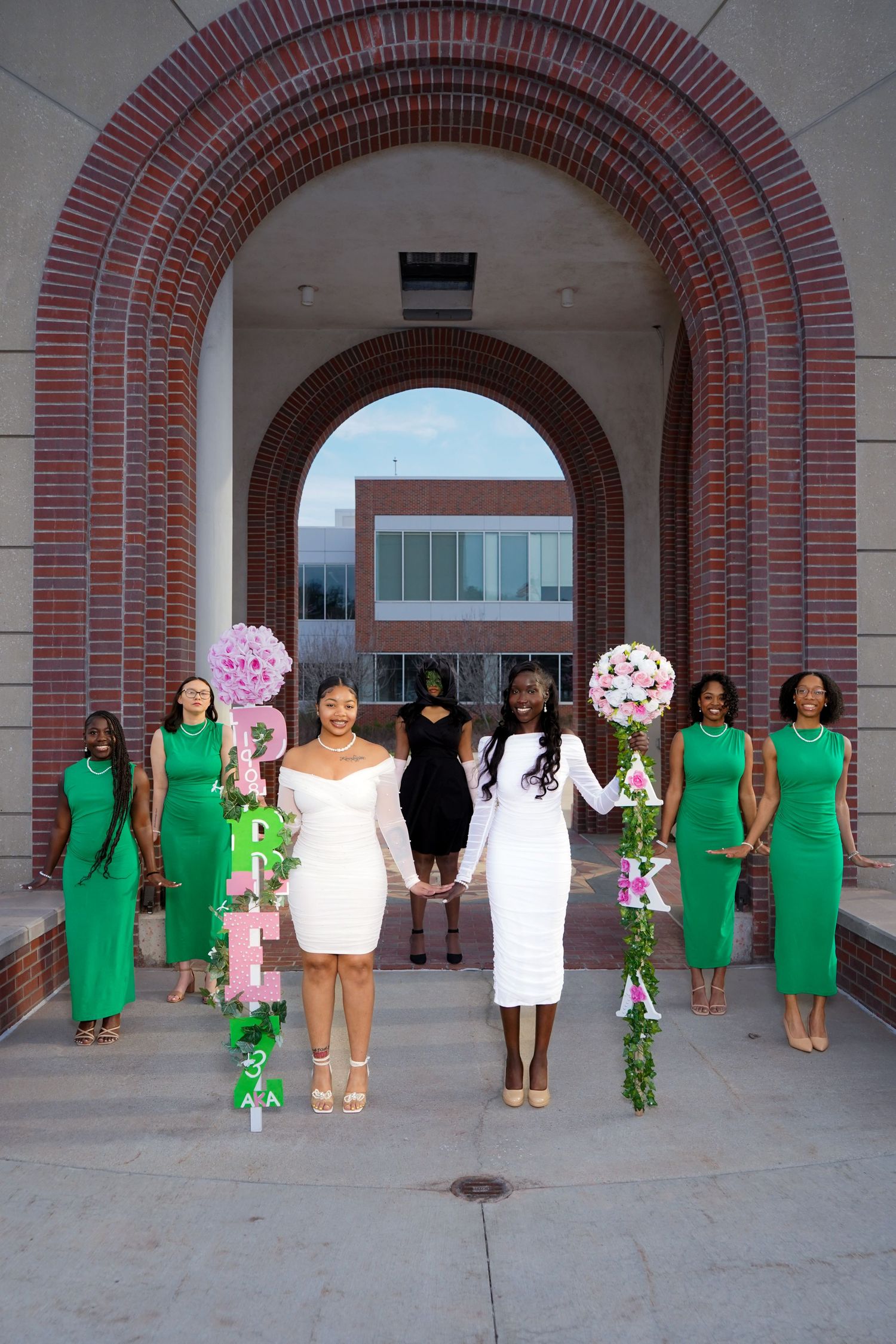Group photo series under brick arches with people wearing coordinated green and white dresses.