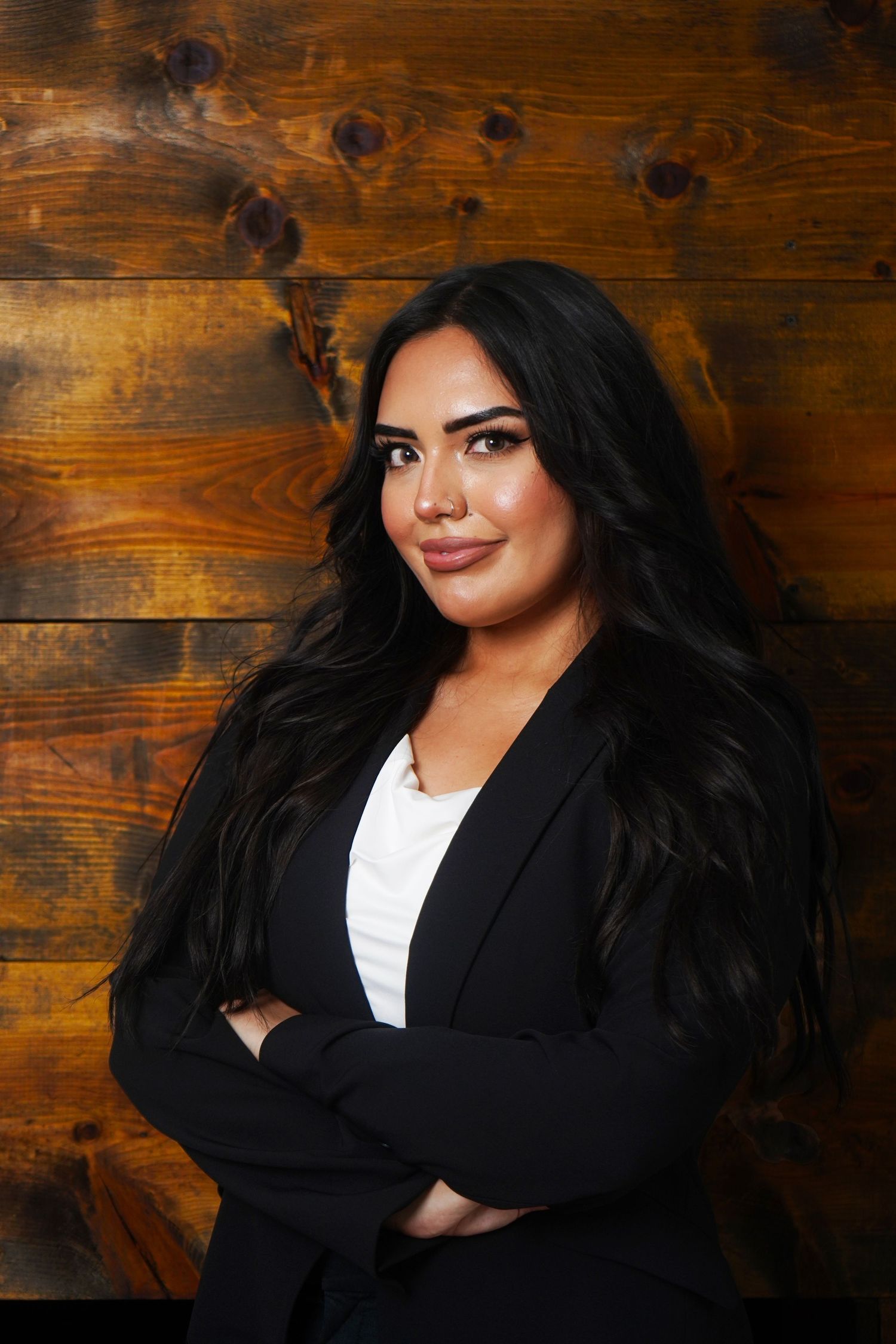 Professional portrait series against wooden backdrop features black blazer and white top.