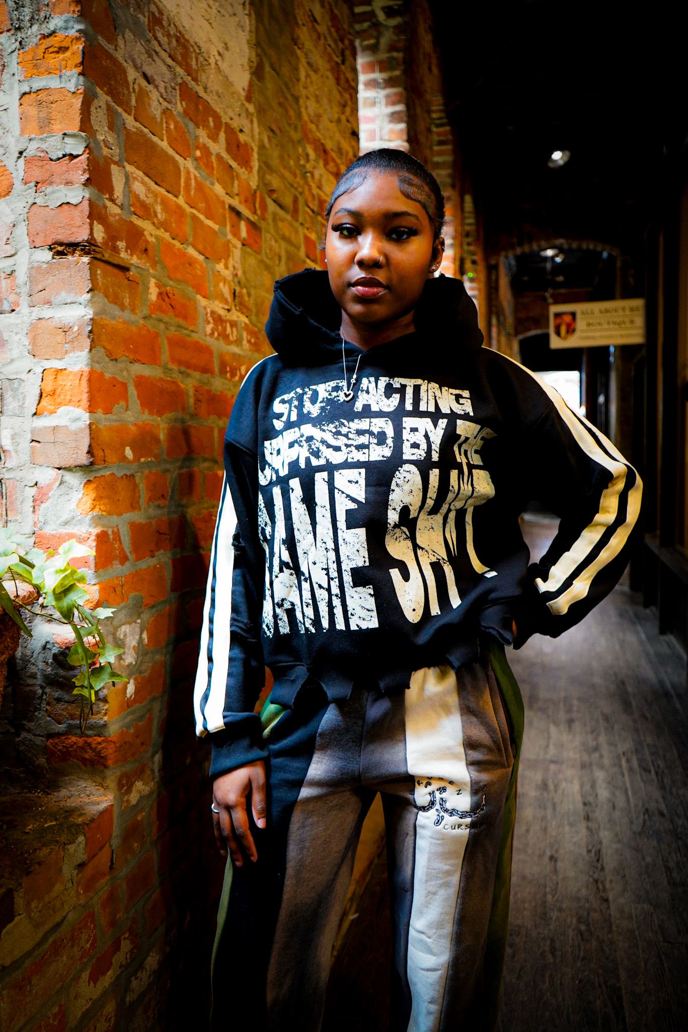 Black graphic jacket shown in multiple angles against brick wall backdrop.