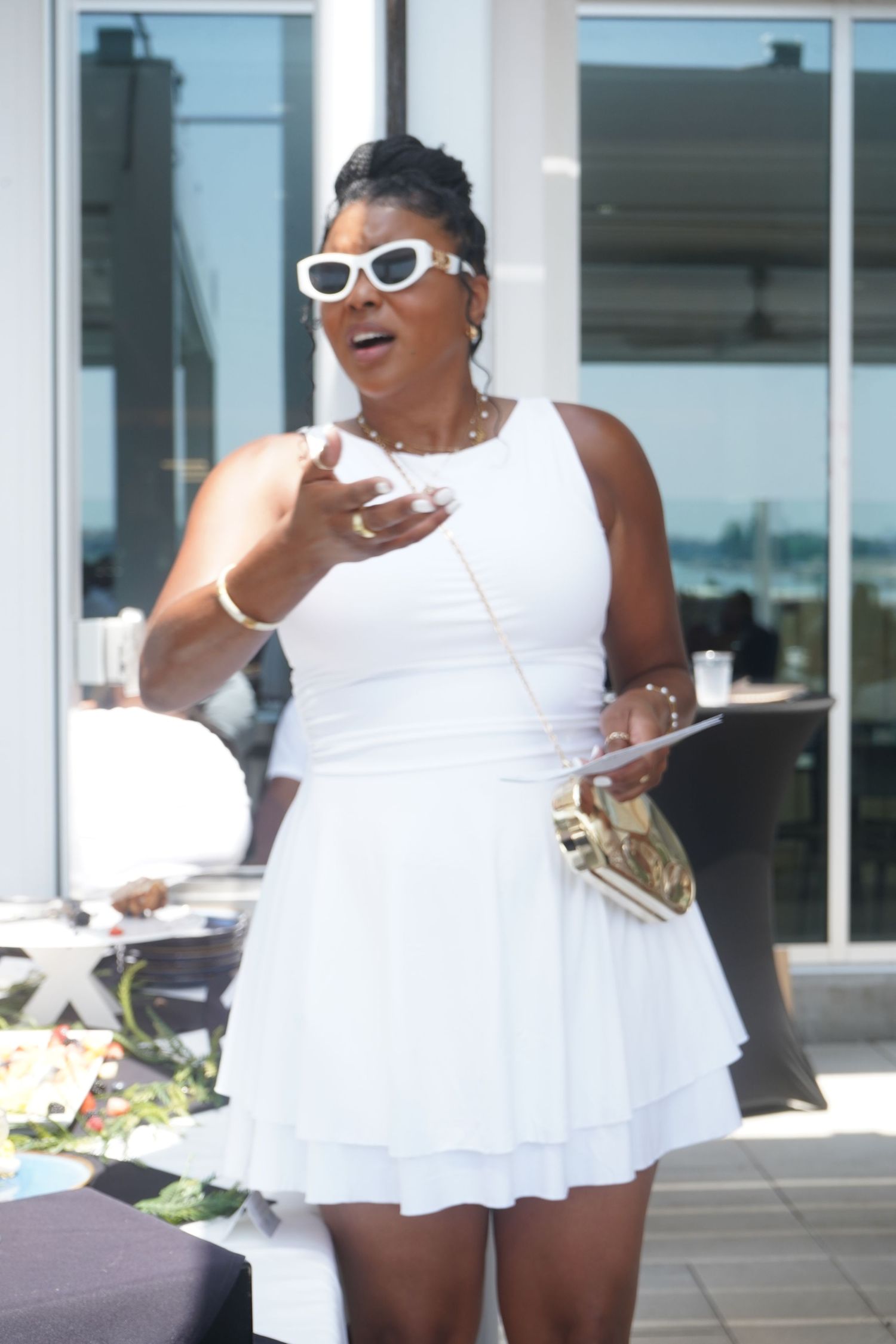 Women in matching white dresses and sunglasses enjoying an outdoor brunch event.