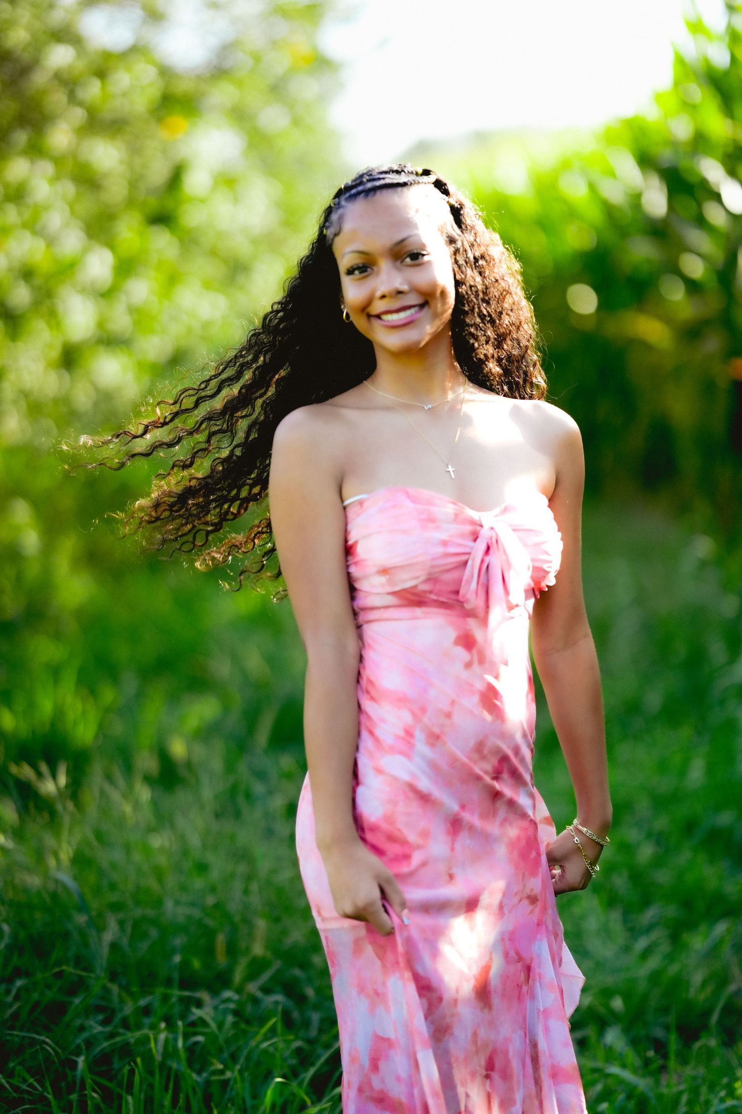 Dynamic outdoor portraits in pink tie-dye dress with natural green foliage background.
