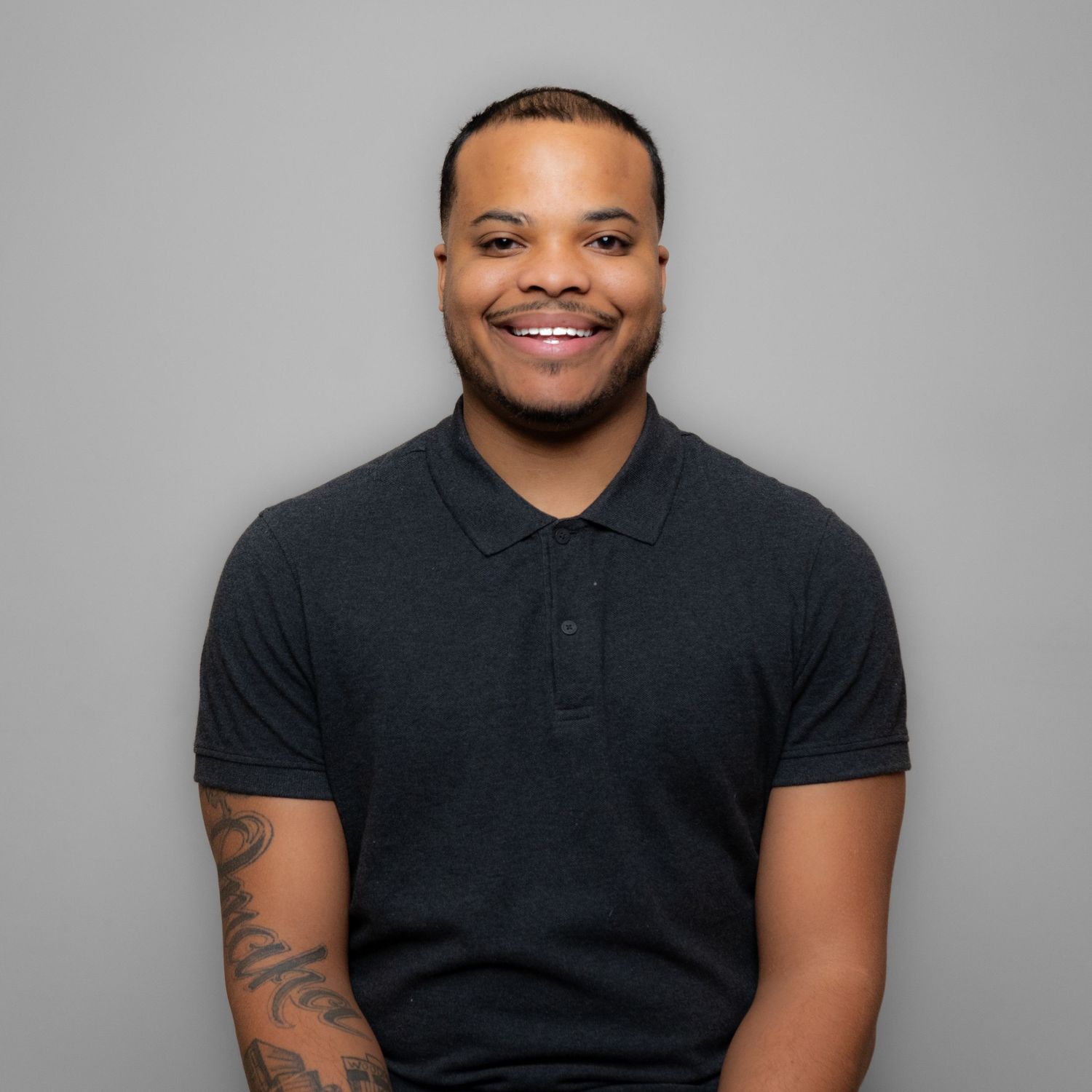 Professional portrait of person in business attire against red wooden background.