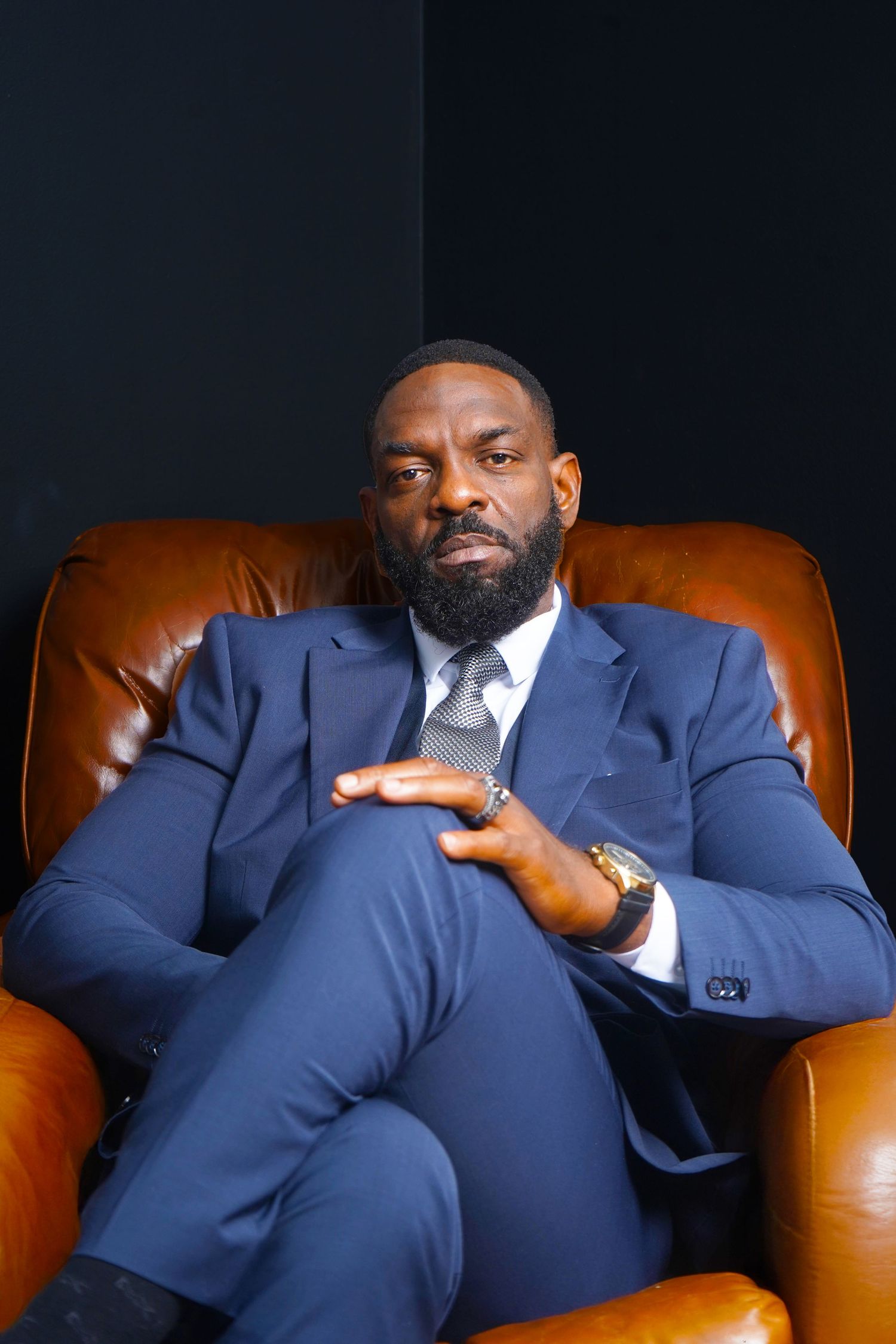 Professional portrait series showing a person in a navy suit seated in a brown leather chair from different angles.
