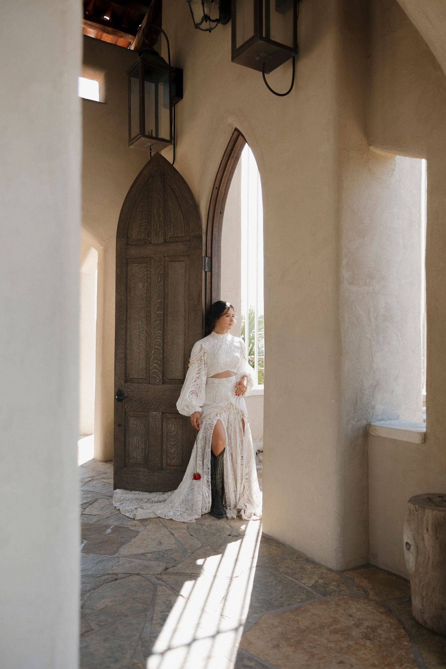 A wedding dress silhouette against arched doorway with dramatic lighting.
