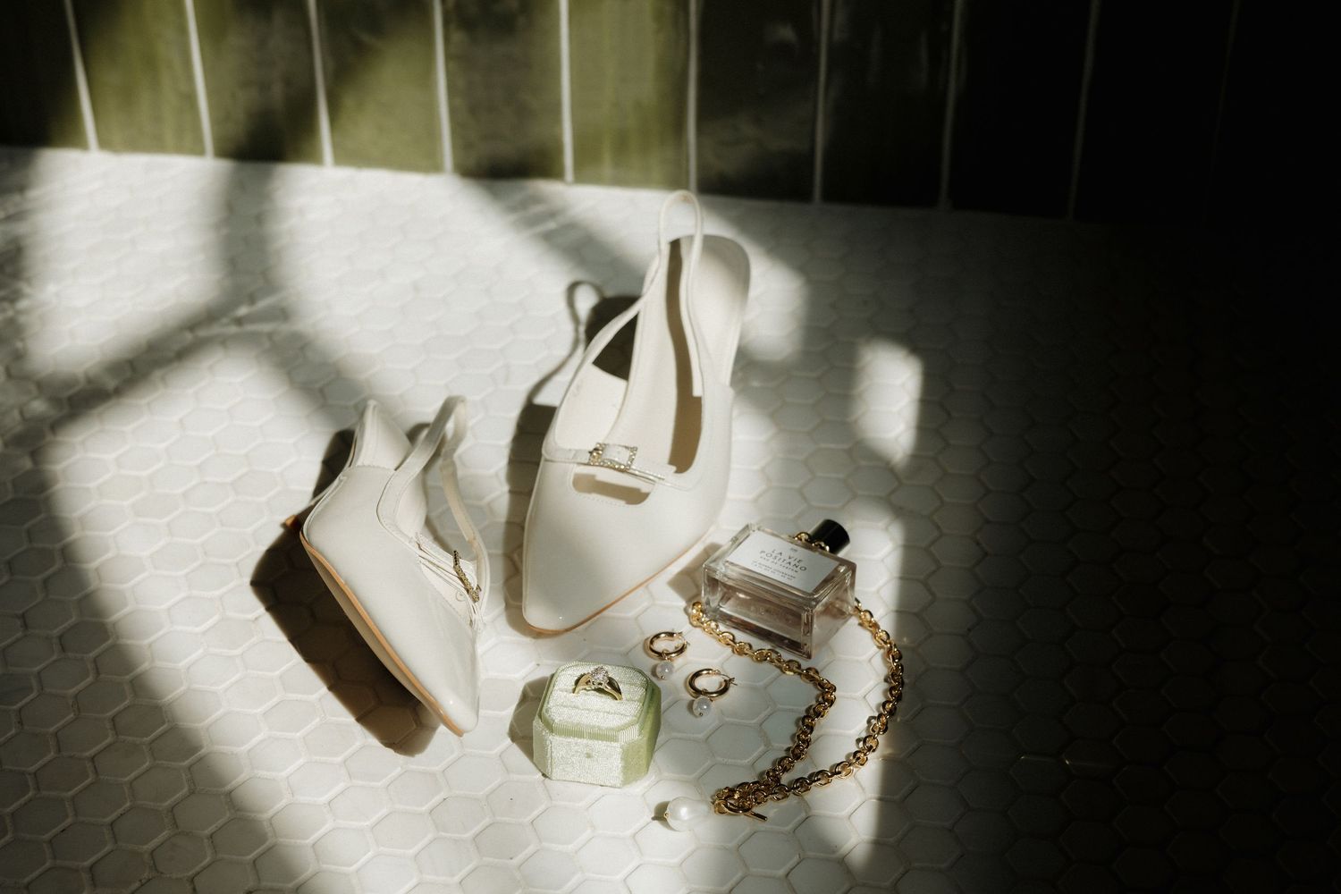 White bridal shoes and jewelry arranged artistically in dramatic window light.
