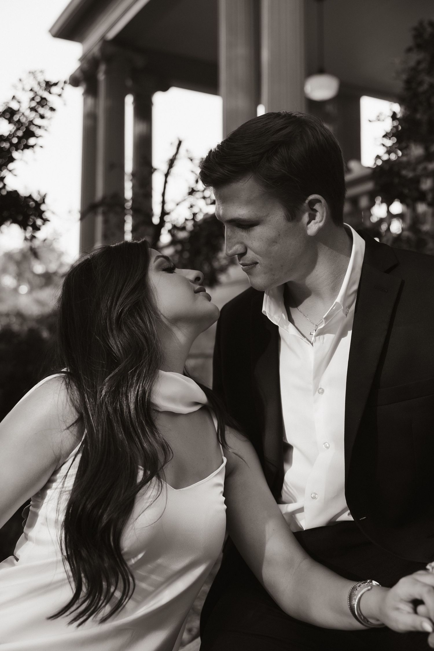 Intimate romantic moment captured between couple in formal wear on porch.