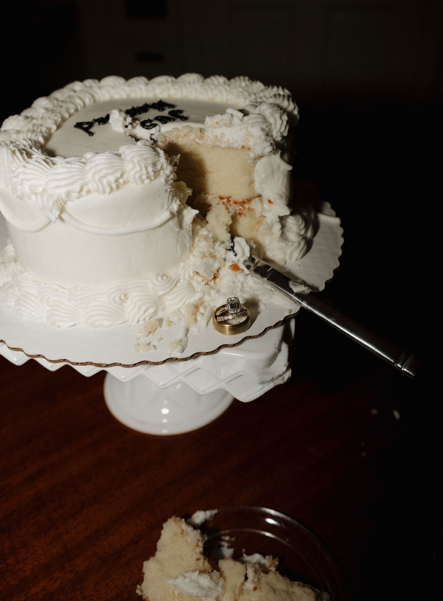 A series of images showing a cake being cut and served on a wooden table with white frosting and dark filling.