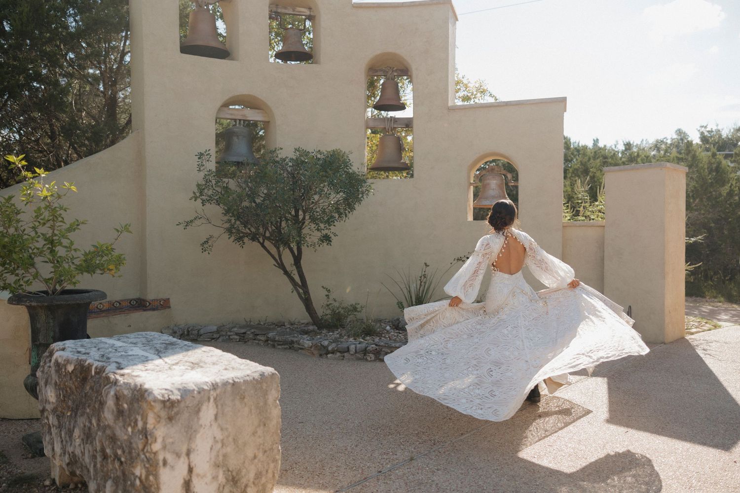 A bridal portrait in flowing dress against Mediterranean style architecture.