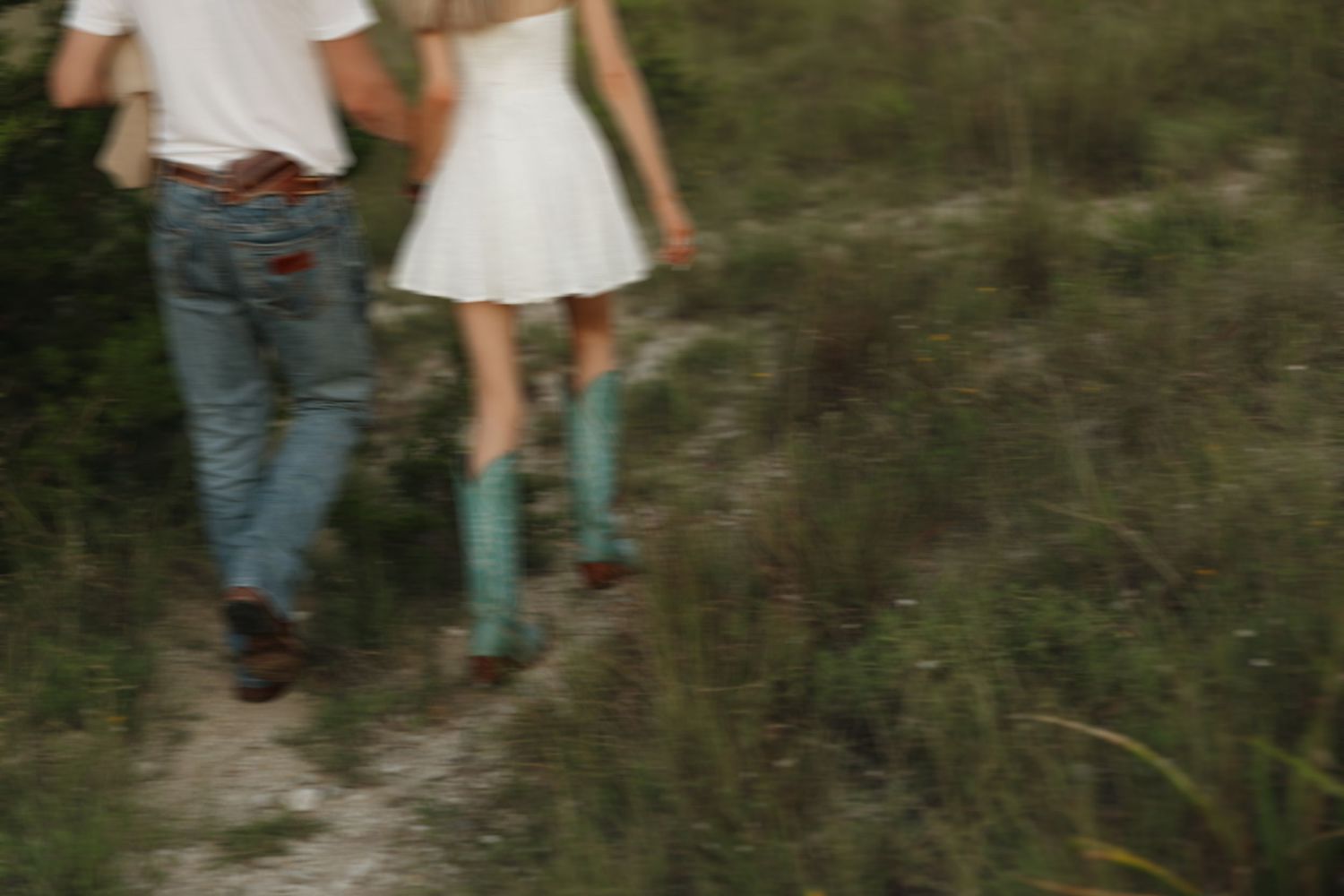 Close-up view of couple's legs walking together on a dirt path.