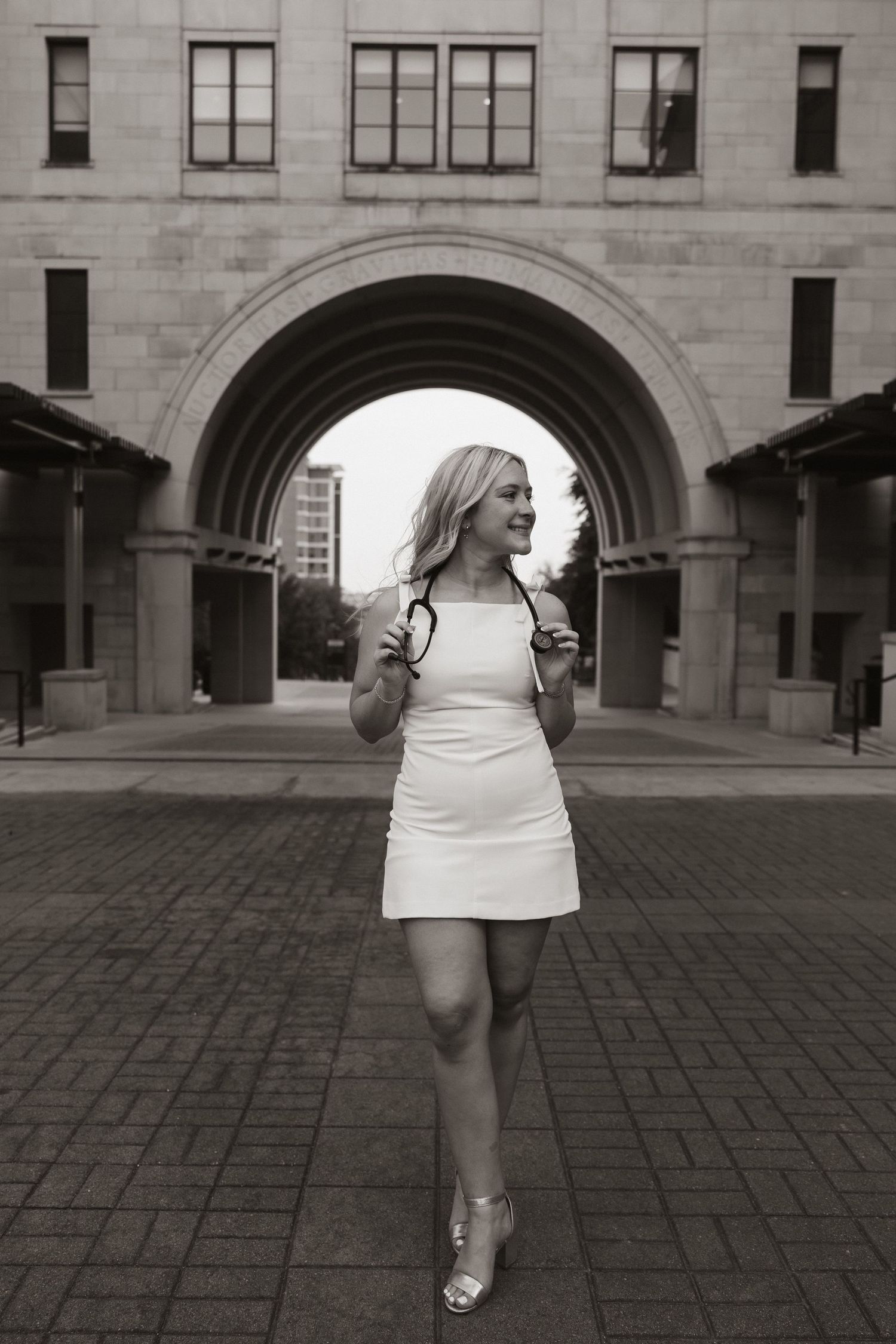 Black and white photo of person in white dress standing under an architectural archway.