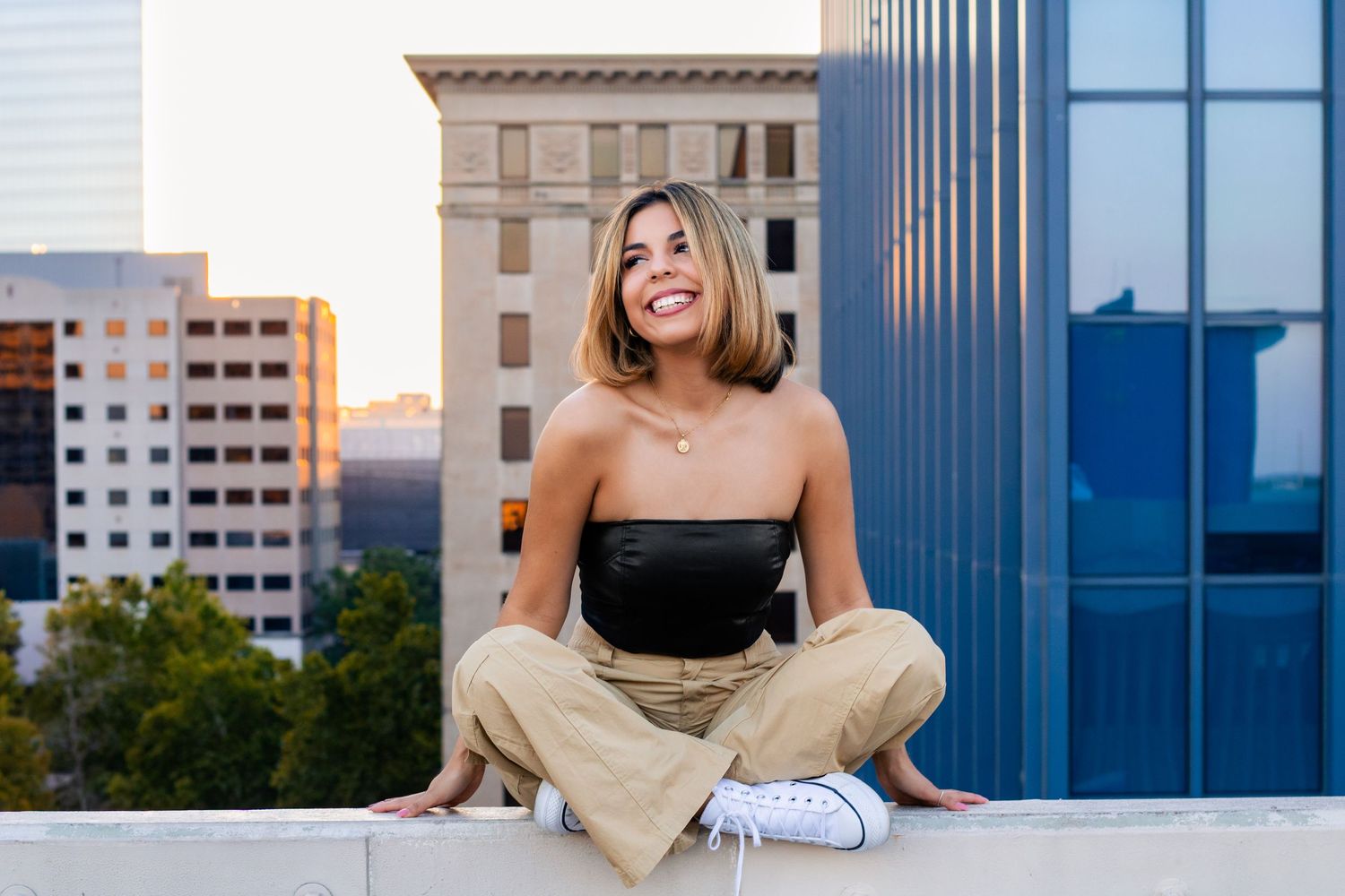 OKC senior on rooftop parking garage with skyline at sunset, photographed by Edmond & OKC photographer Taylor Maze, natural light portraits.