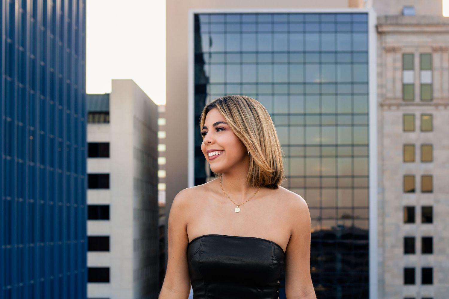 OKC senior on rooftop parking garage with skyline at sunset, photographed by Edmond & OKC photographer Taylor Maze, natural light portraits.