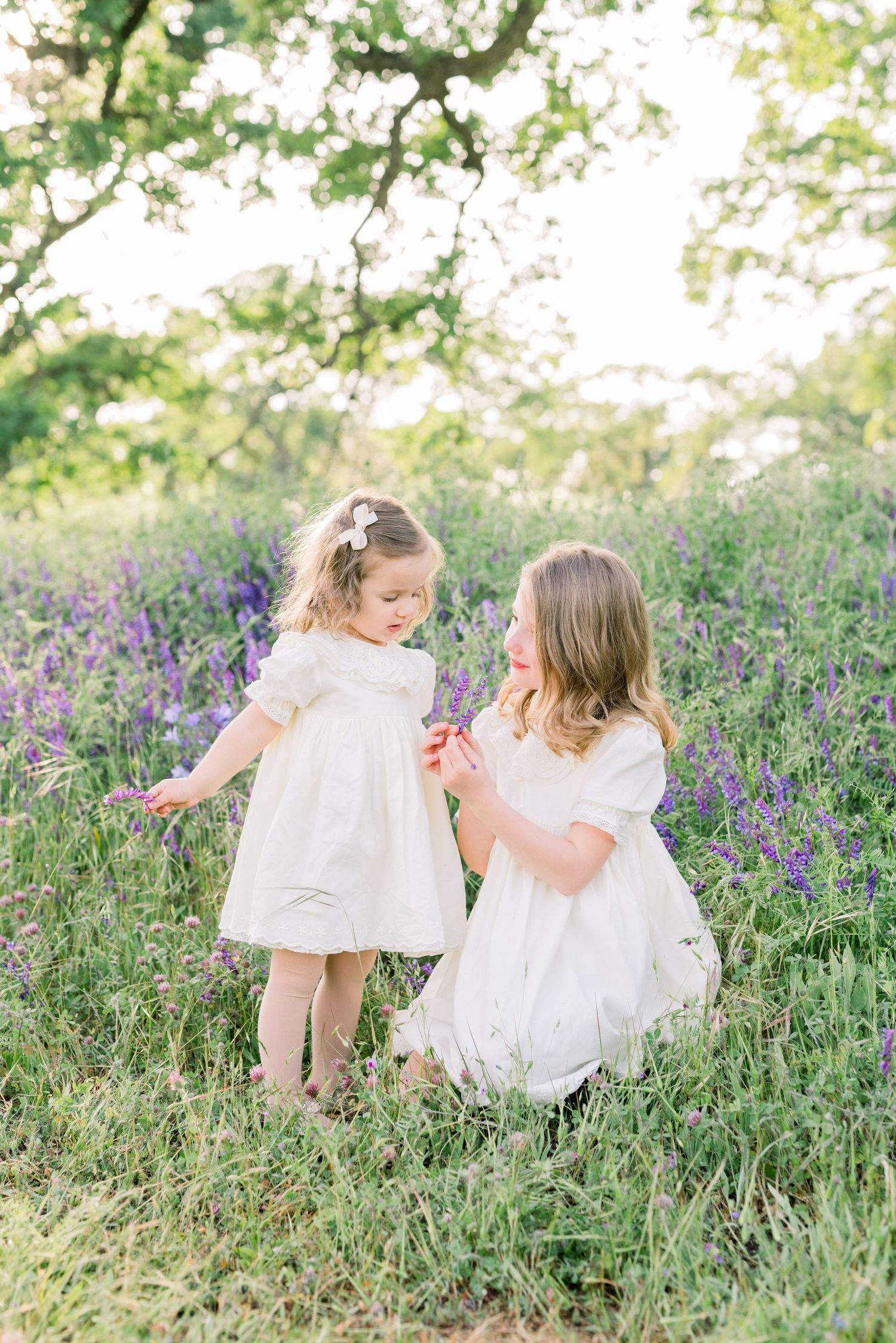 Candid moment of sisters sharing a moment in a field, taken by Boise family photographer Natalya Mark.