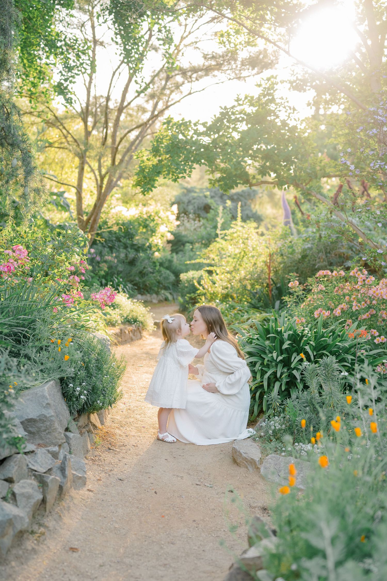 Pregnant woman in neutral dress during outdoor Boise maternity shoot, golden hour light snuggling her daughter
