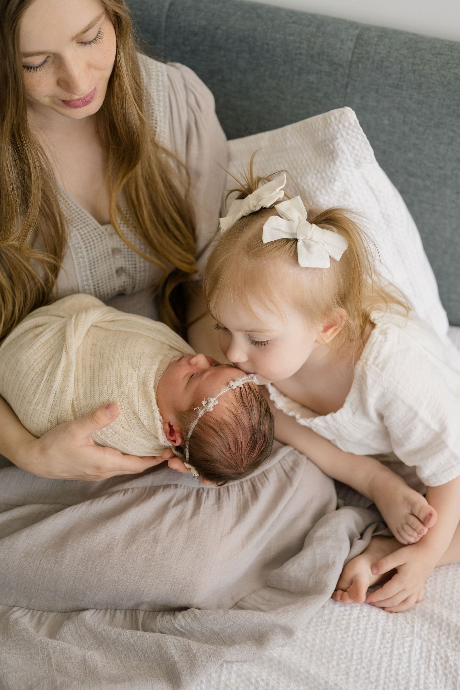 Mom snuggling her babies on a bed during her Newborn photoshoot shot by Natalya Mark Photo