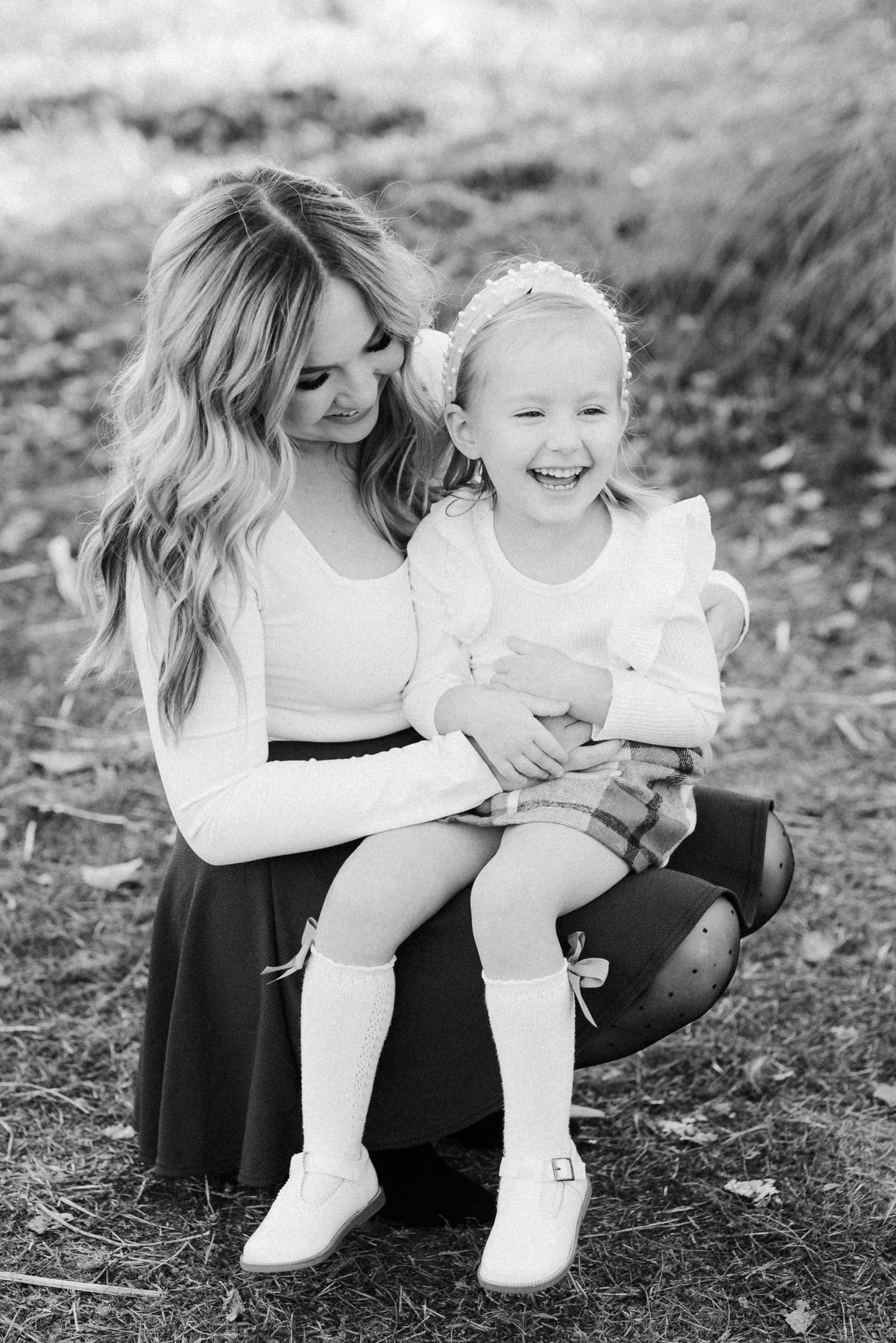 Mom holding toddler daughter during candid Boise family photography session.