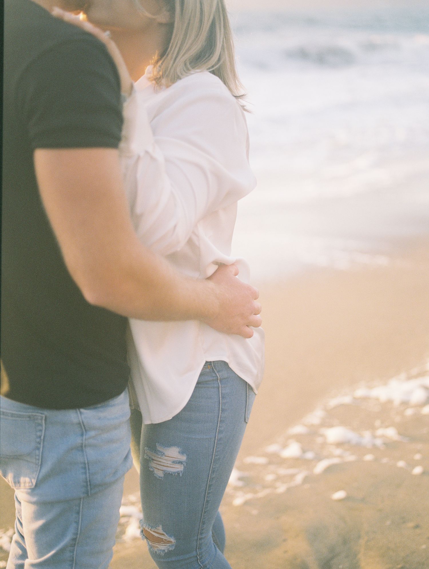 Couple laughing together during golden hour engagement session, 35mm film by Natalya Mark.
