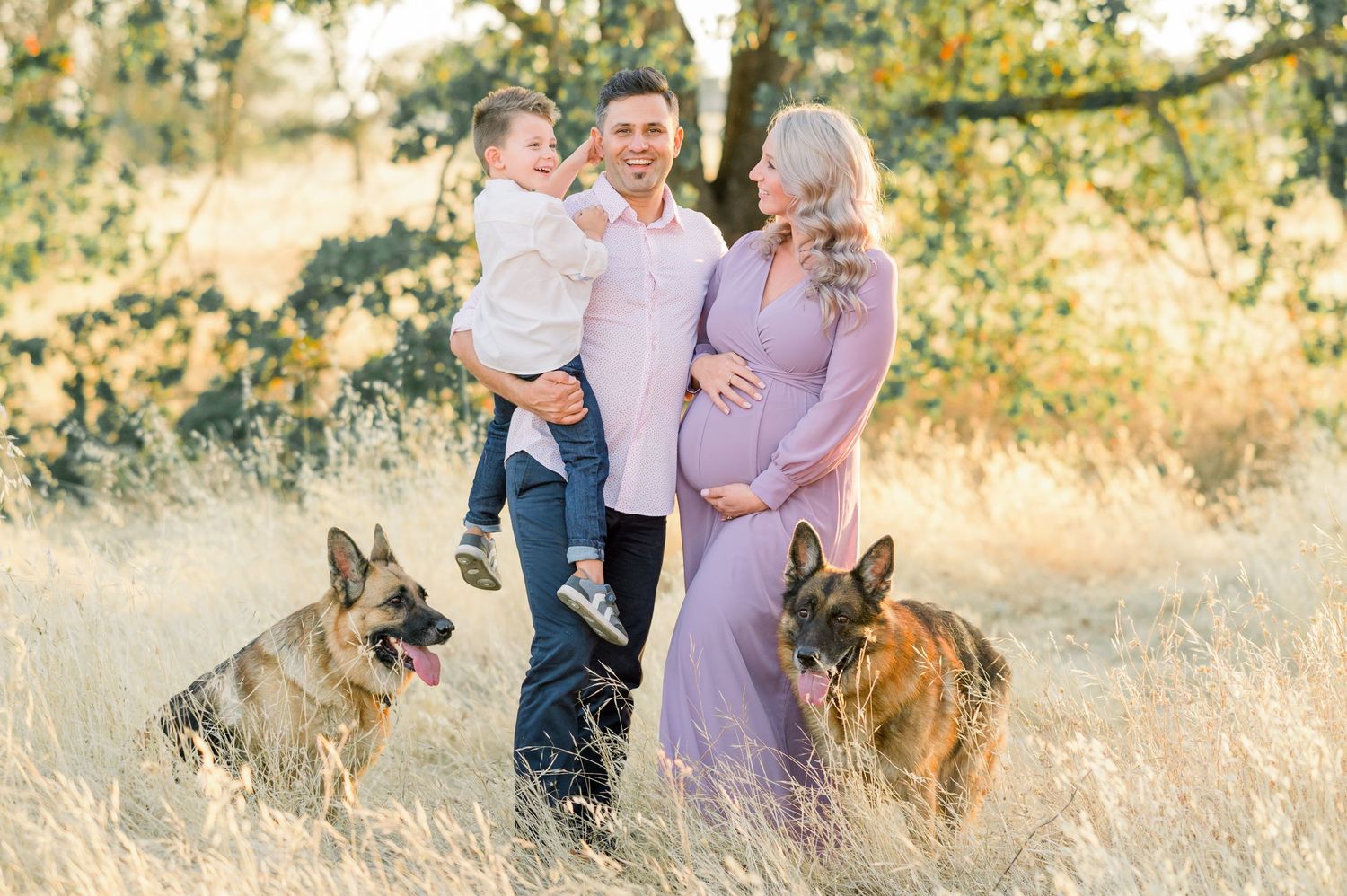 Pregnant woman in neutral dress during outdoor Boise maternity shoot, golden hour light with family and dogs.