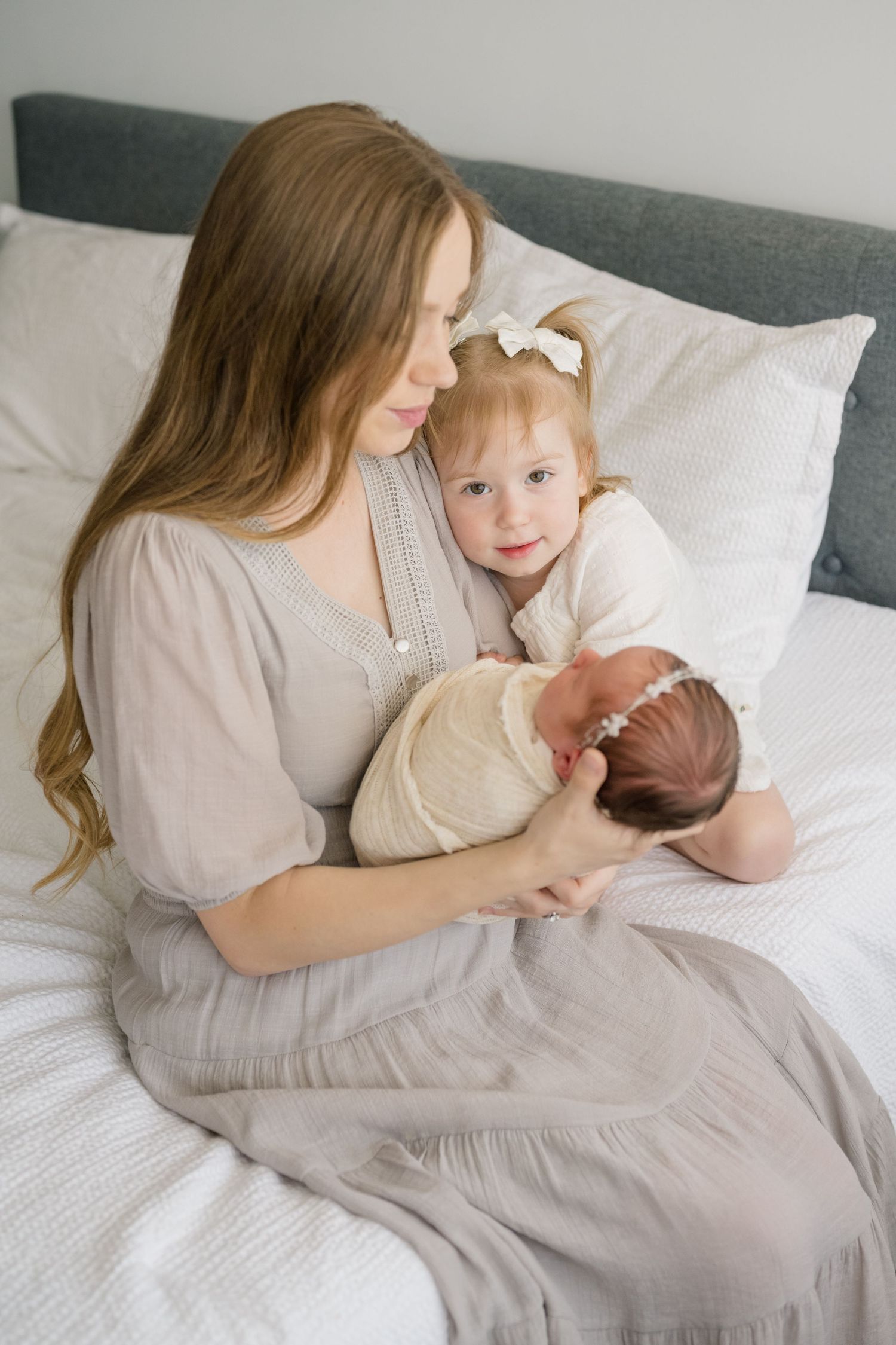 Mom snuggling her babies on a bed during her Newborn photoshoot shot by Natalya Mark Photo