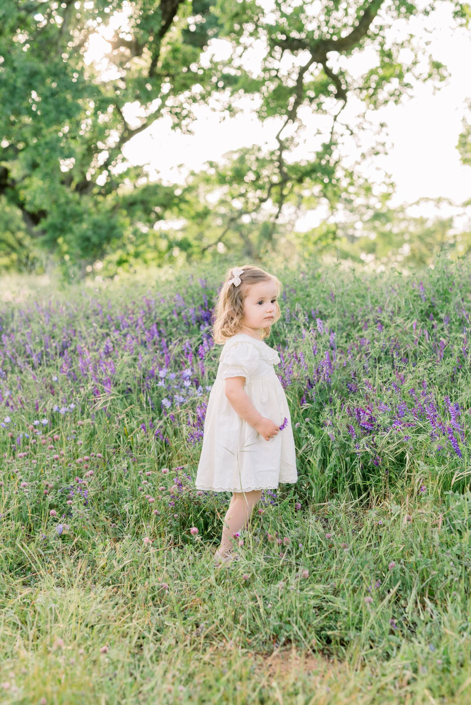 Candid moment of a little girl looking at flowers in a  field, taken by Boise family photographer Natalya Mark.
