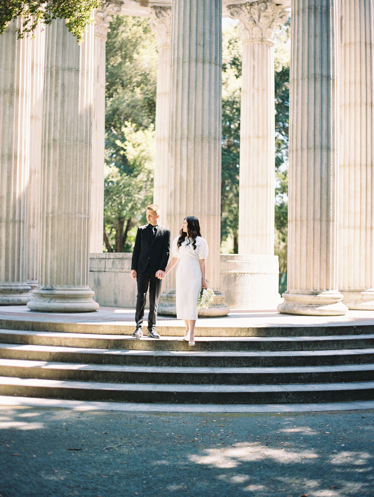Film photo of couple embracing outdoors with sun flare in Plugas Water temple in the Bay Area