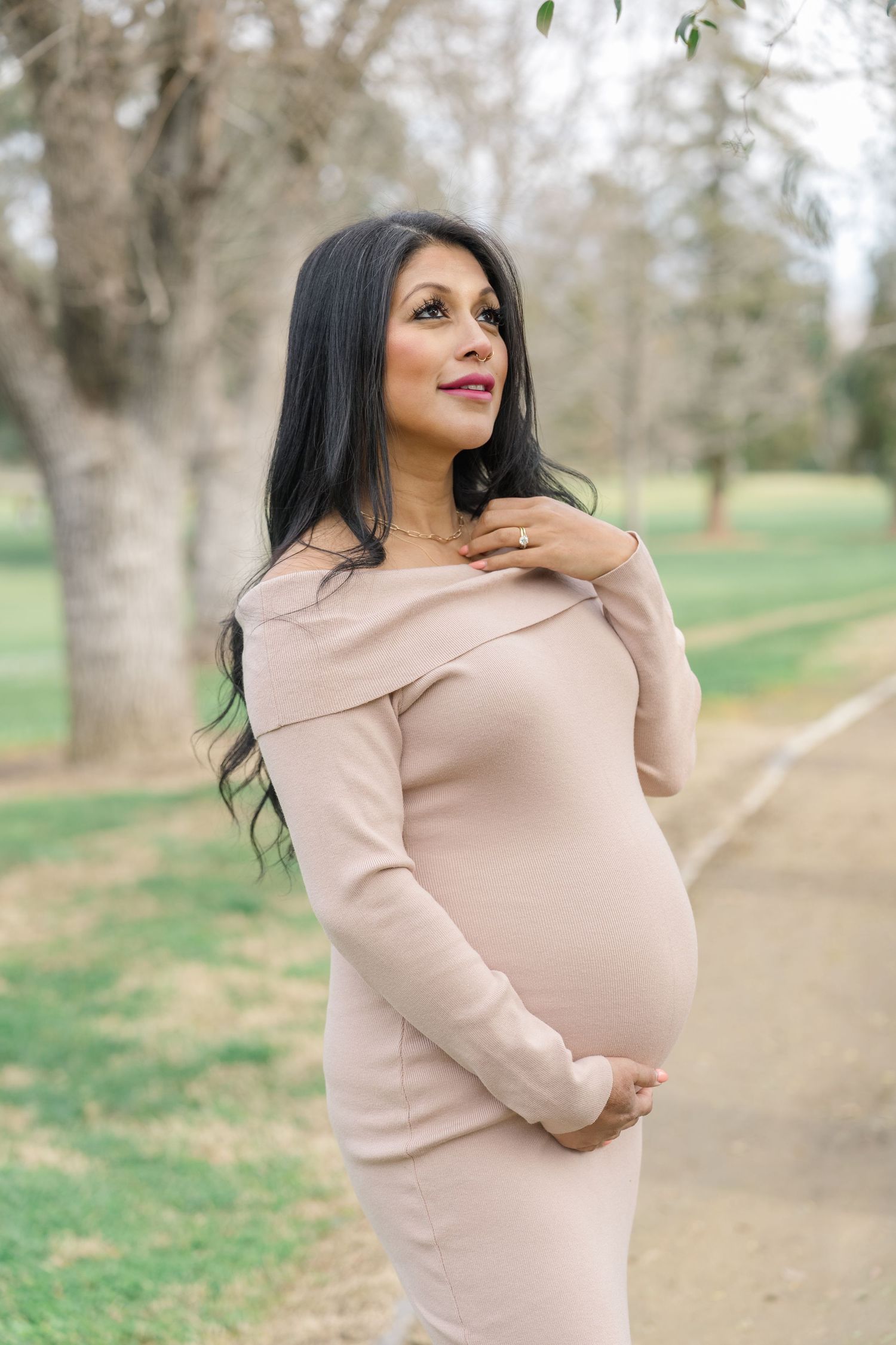 Pregnant woman in neutral dress during outdoor Boise maternity shoot, golden hour light.