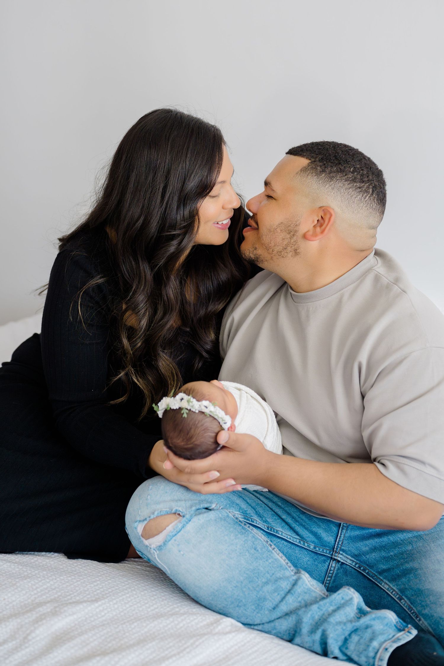 Family hugging on bed with newborn daughter in Boise