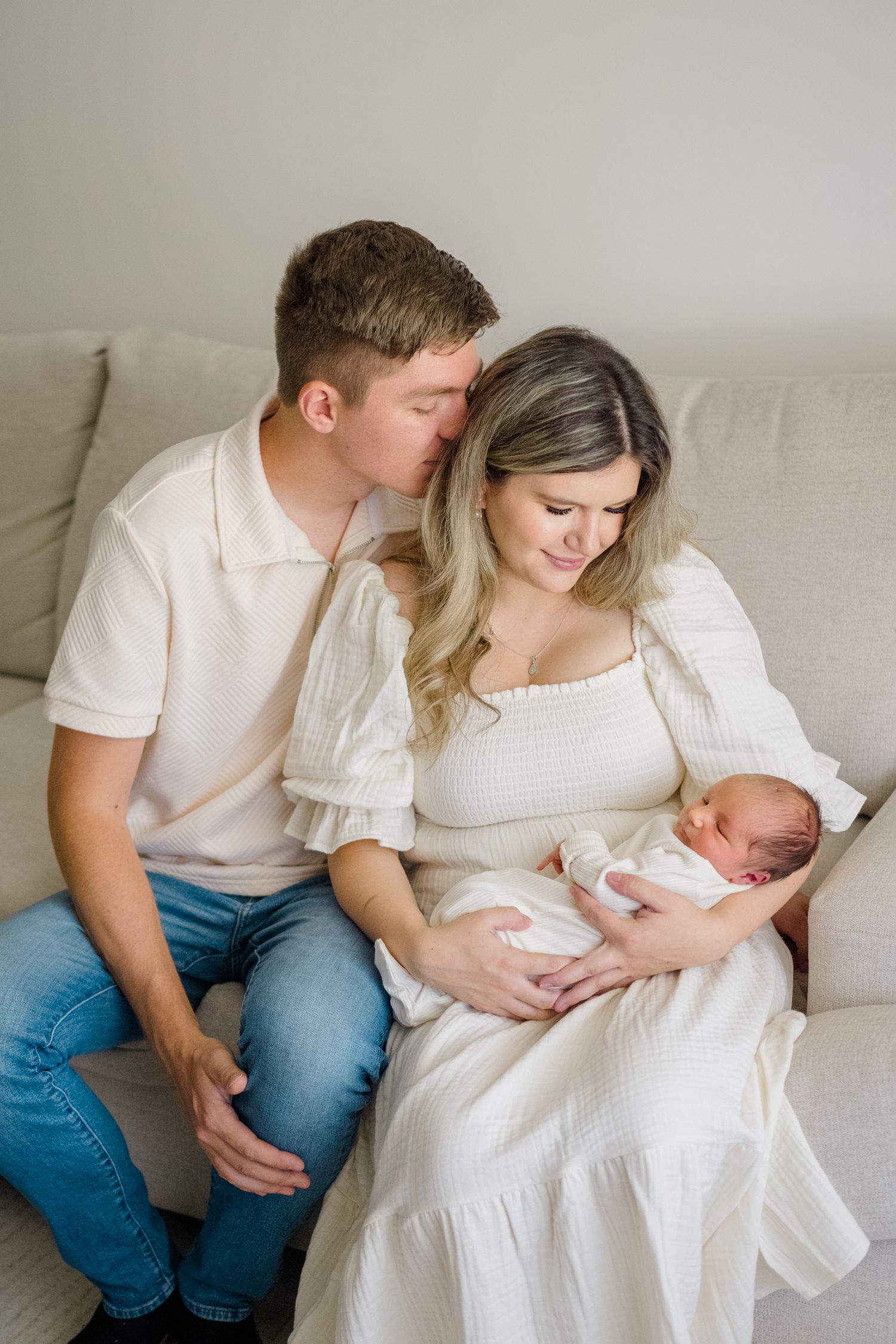 Family snuggling their baby on a bed during her Newborn photoshoot shot by Natalya Mark Photo