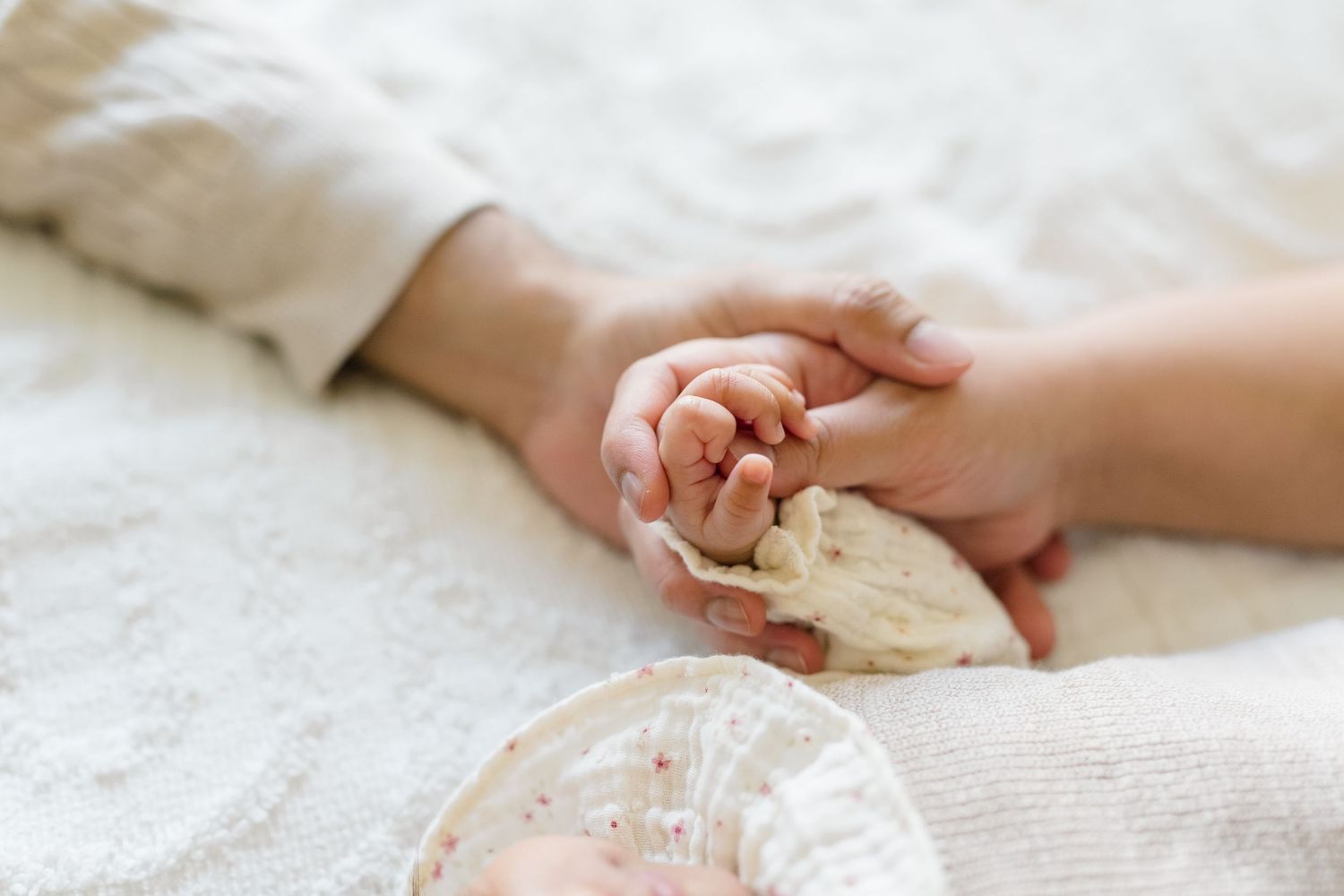 Mom and dad holding their newborn daughters hand during a newborn shoot in Kuna Idaho