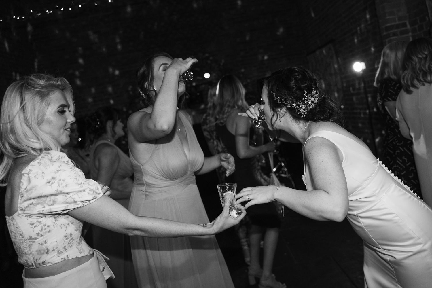 Black and white photo of people dancing and celebrating at what appears to be a party or nightclub.