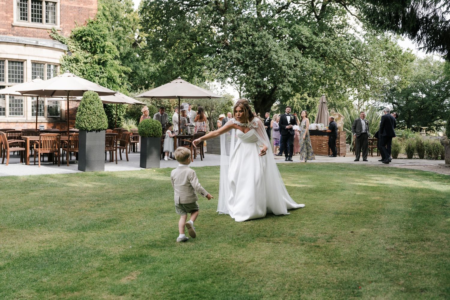 A couple walks together across a lush green lawn during an elegant outdoor wedding celebration.