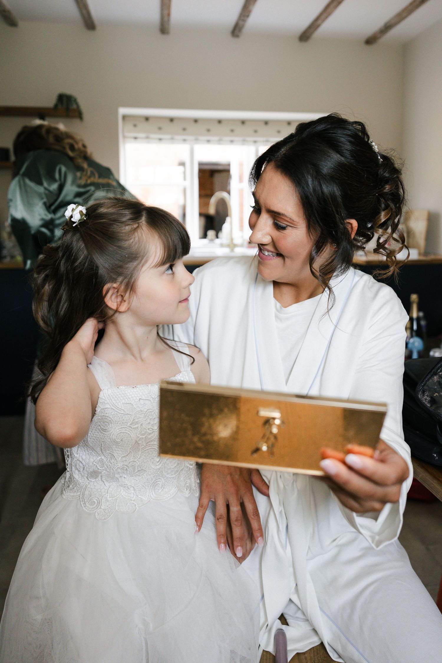 Two people in white attire share an intimate moment while looking at a gift box during a special occasion.