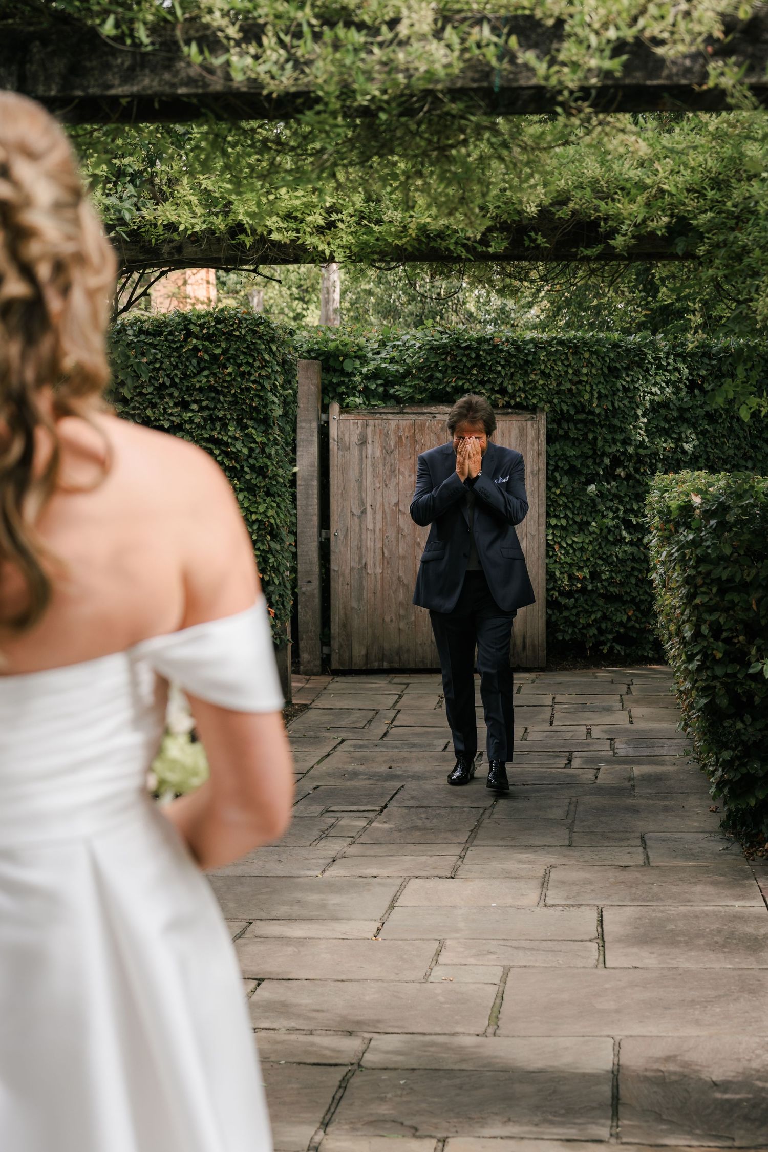 A first look moment between a bride in white and groom in dark suit during an outdoor garden wedding ceremony.