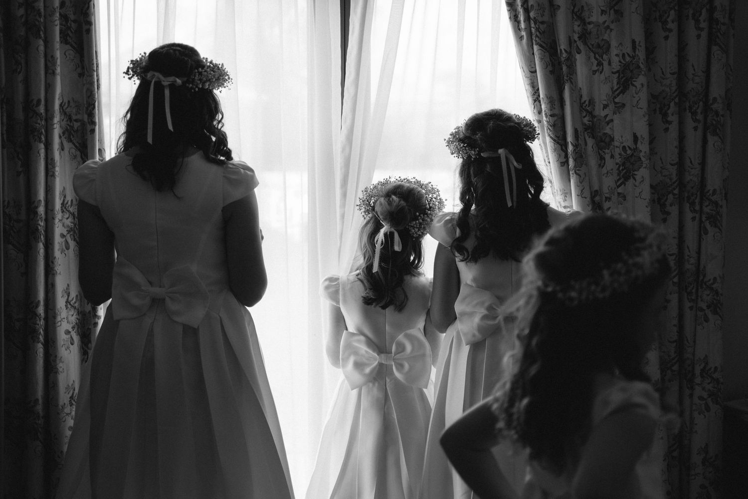 Silhouetted figures against bright window with flowing wedding dress visible.