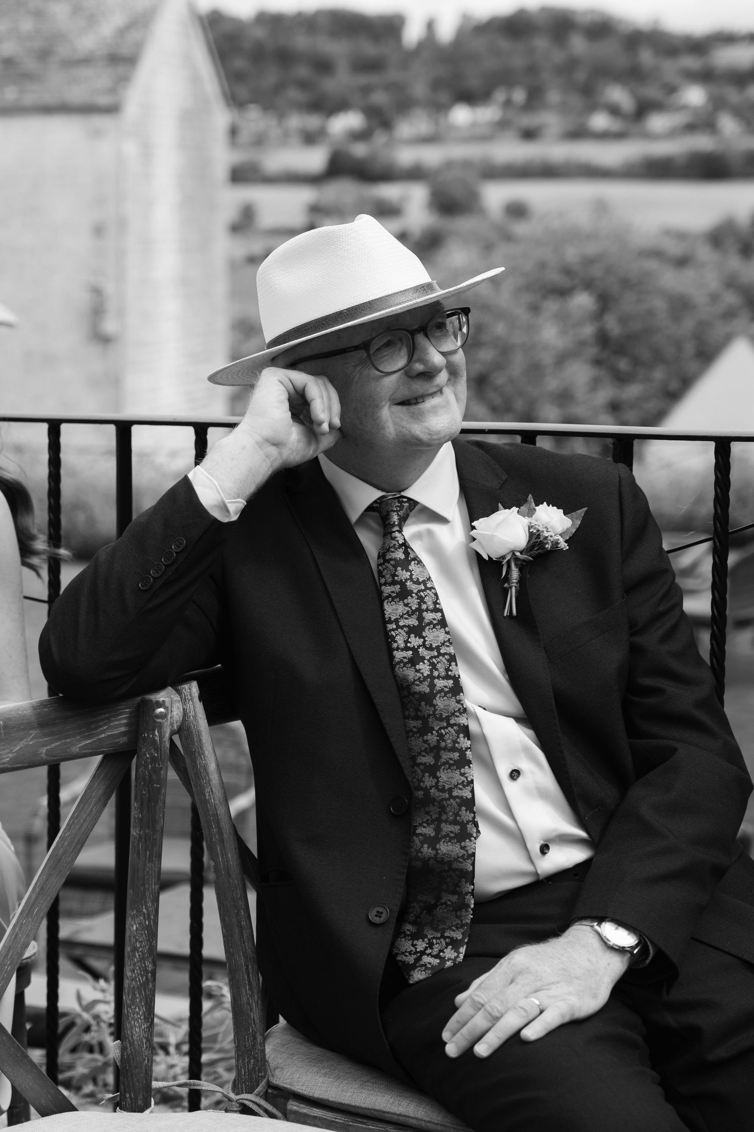 Black and white photos of wedding guests in formal attire relaxing on outdoor patio furniture.