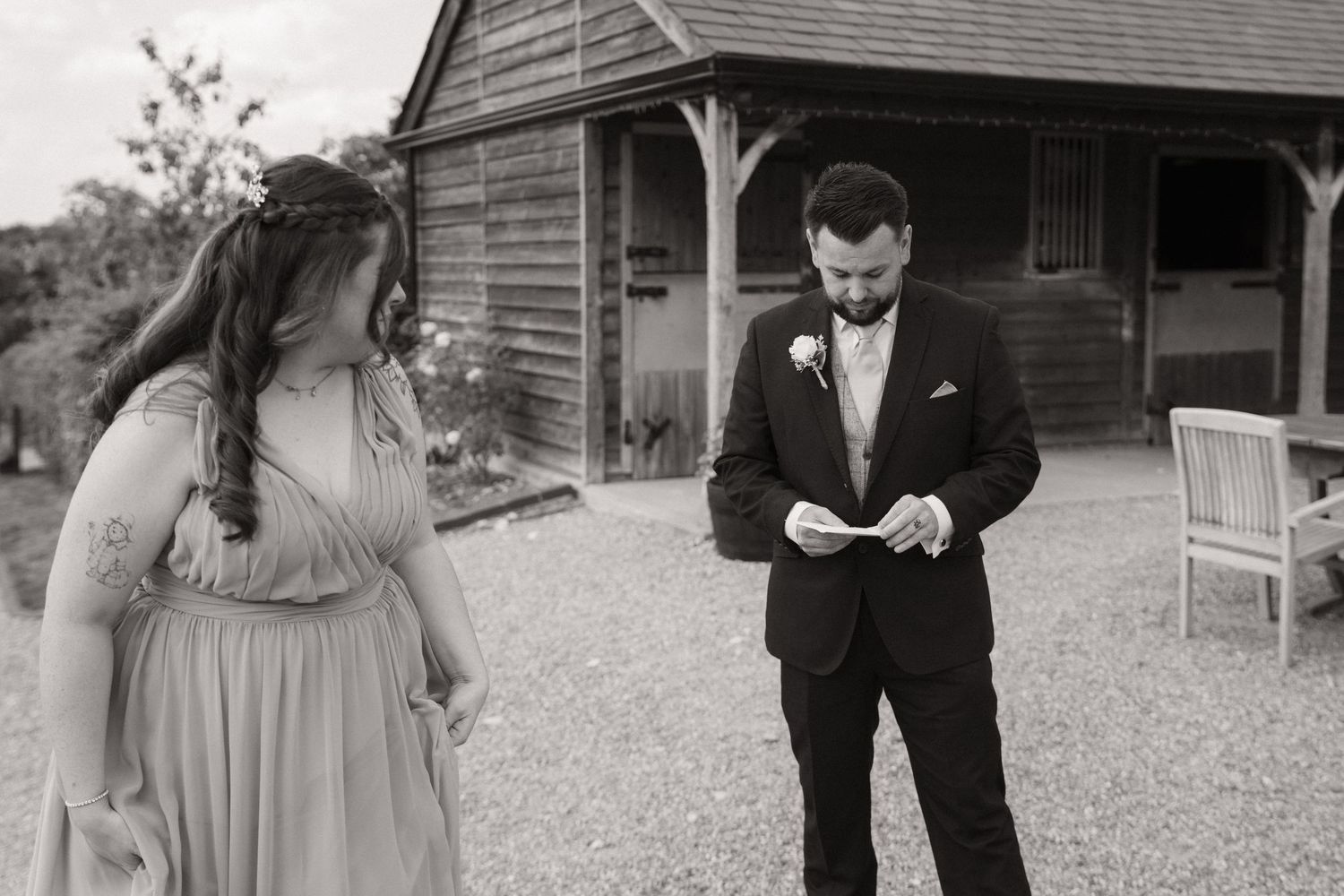 A romantic first look moment between a bride and groom on their wedding day in front of a rustic wooden barn.
