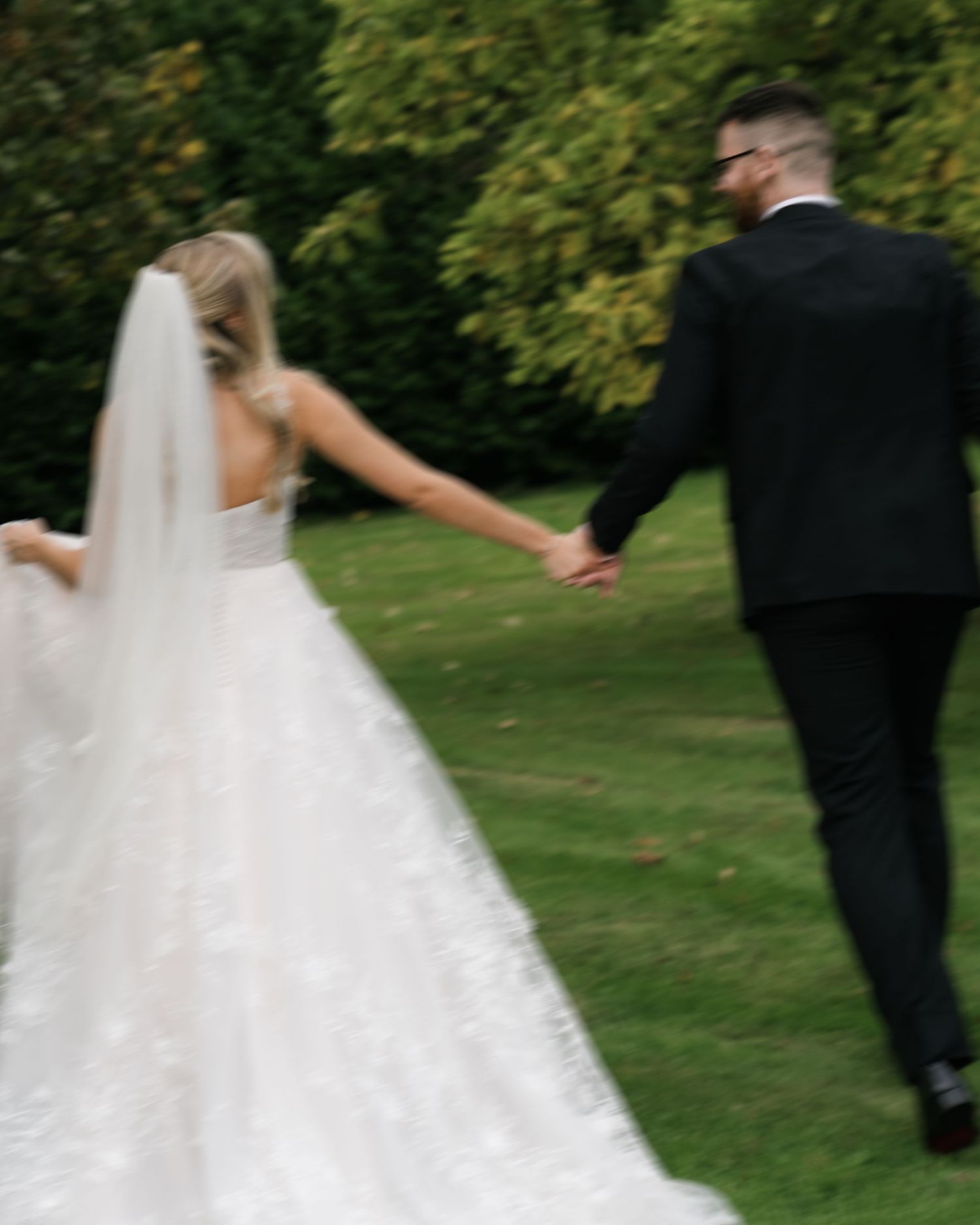 A couple dancing outdoors in a garden setting with the bride wearing a flowing white wedding dress.