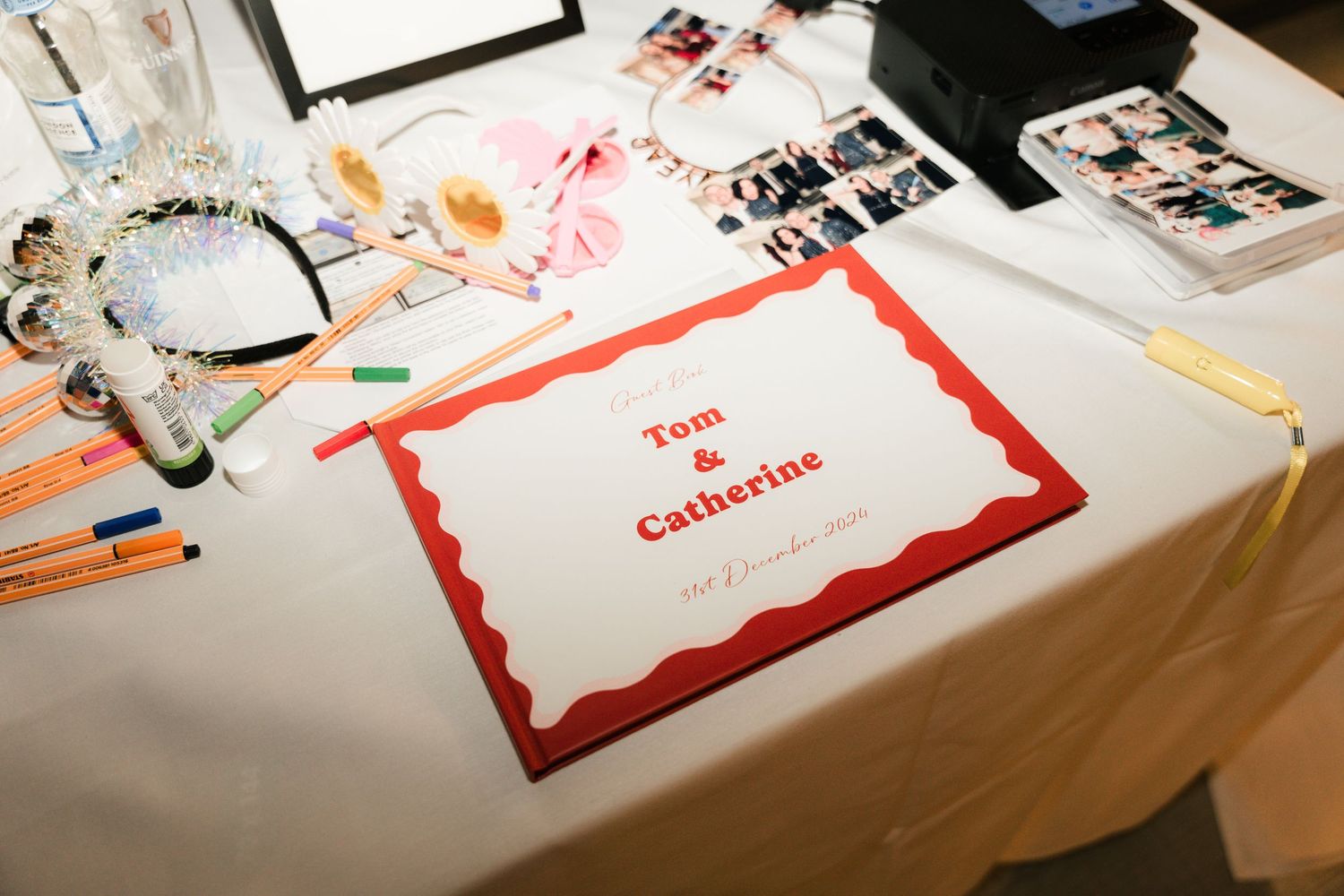 Place cards with red borders and handwritten names laid out on a white tablecloth at an event.