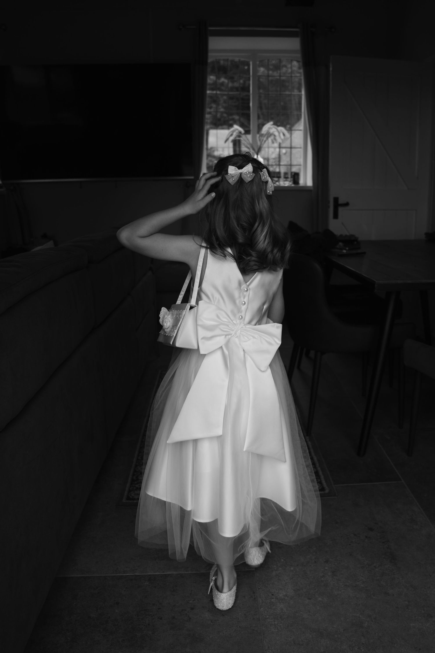 White flower girl dresses displayed in a dark room setting.