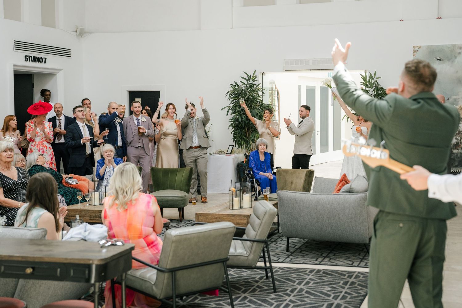 A group of people gathered in a modern living room space with raised arms during a celebratory moment.