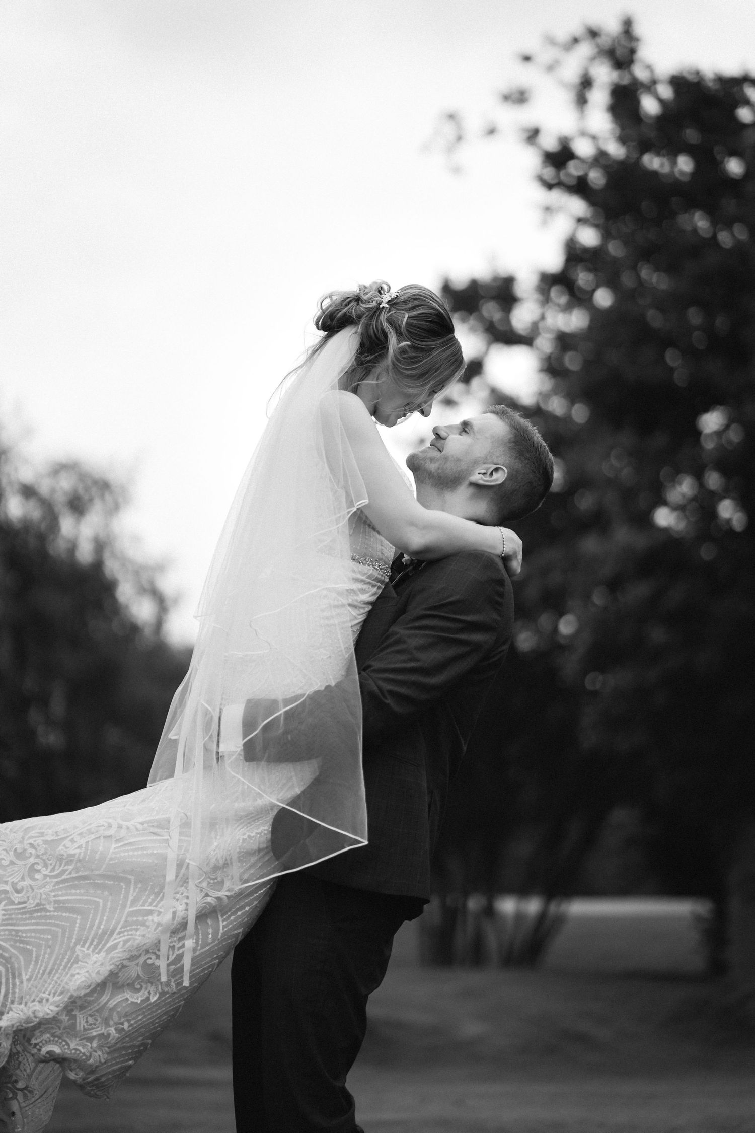 A romantic black and white wedding photo series showing a couple dancing and embracing outdoors.